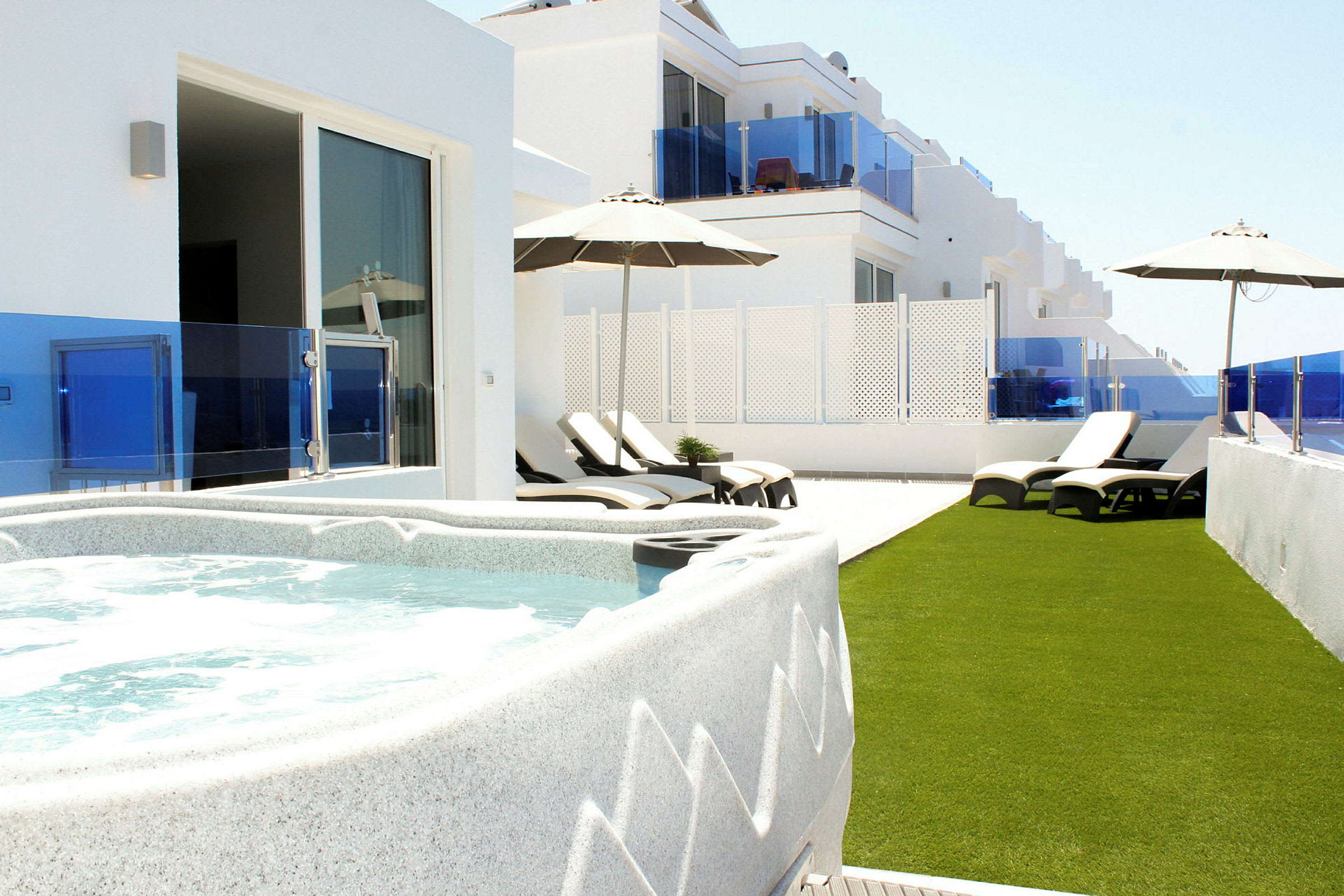 Terrasse med jacuzzi, liggestole og parasoller. (AI-genereret tekst)