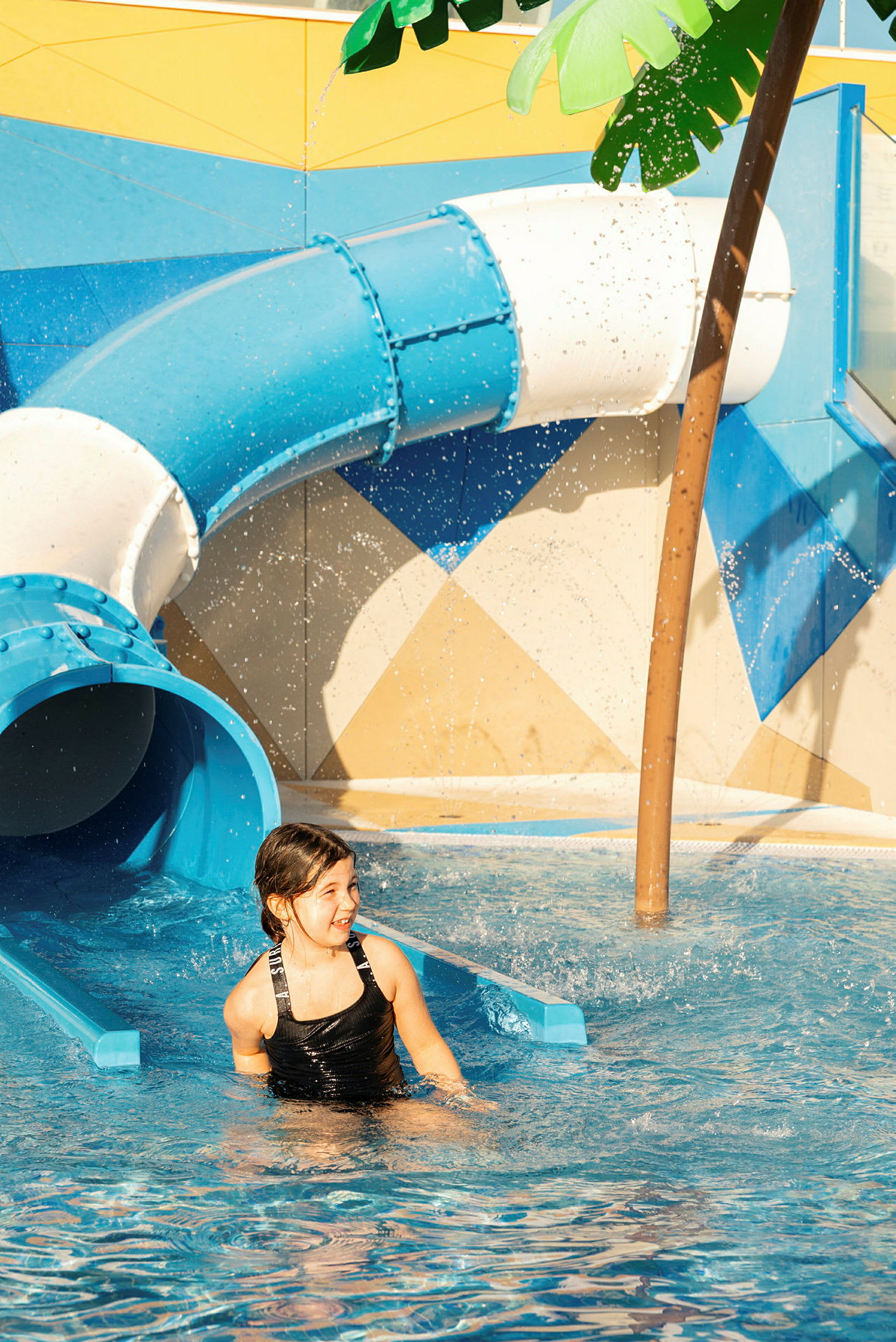 En person ligger i en pool ved enden af en blå vandrutsjebane. (AI-genereret tekst)