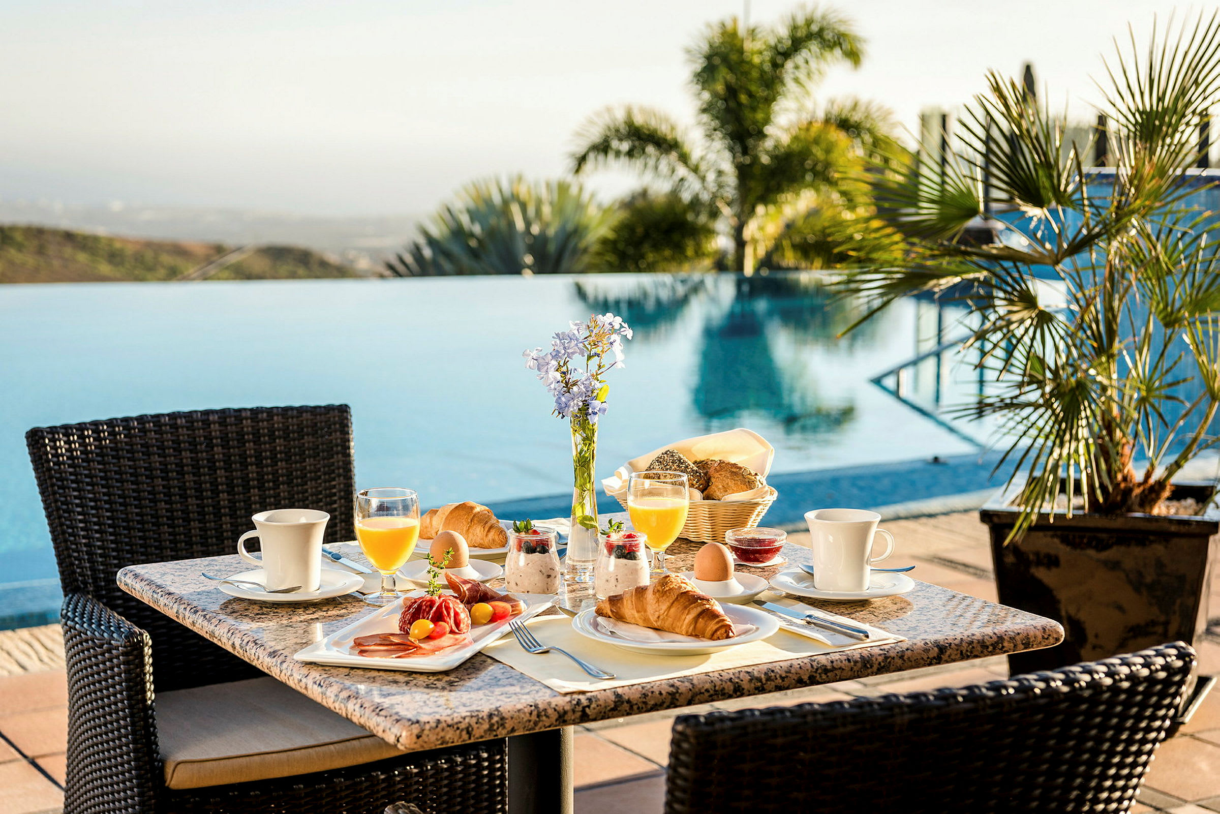 Morgenmad serveret på et bord ved siden af en swimmingpool. (AI-genereret tekst)