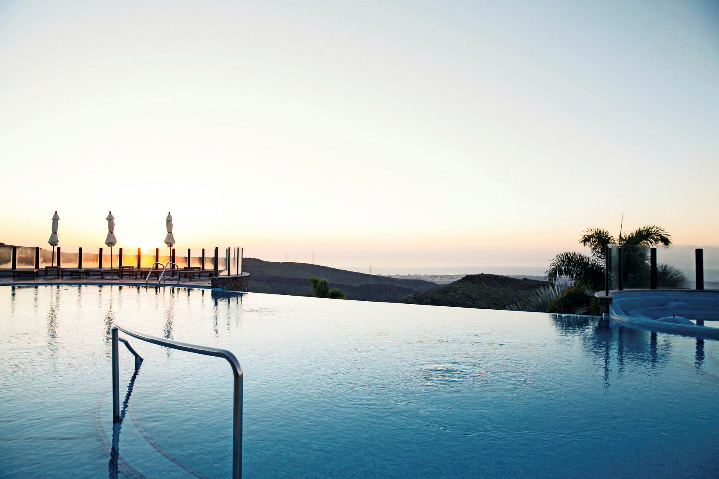 En infinitypool med udsigt over et landskab ved solnedgang. (AI-genereret tekst)