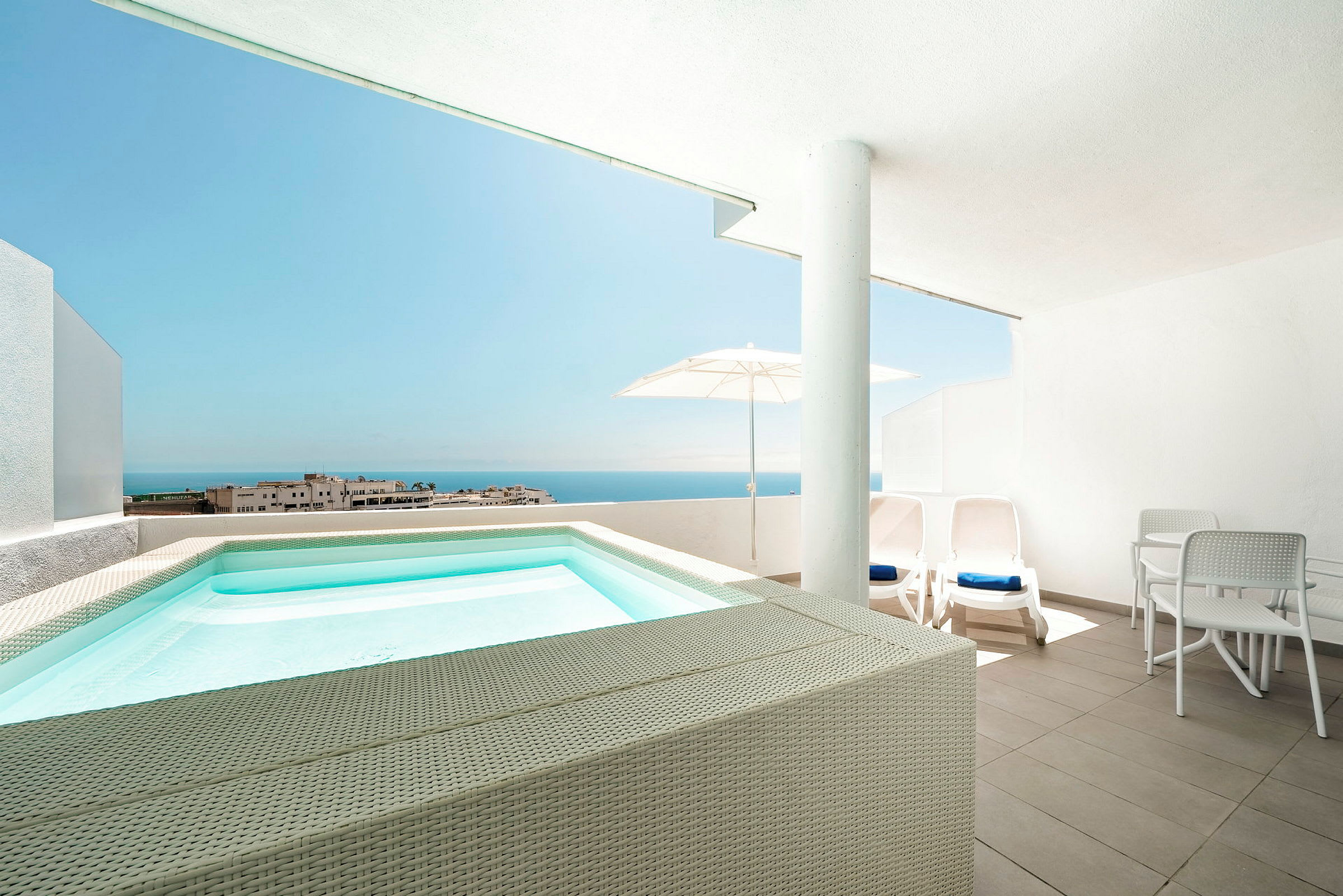 Terrasse med lille pool, liggestole og udsigt mod havet. (AI-genereret tekst)
