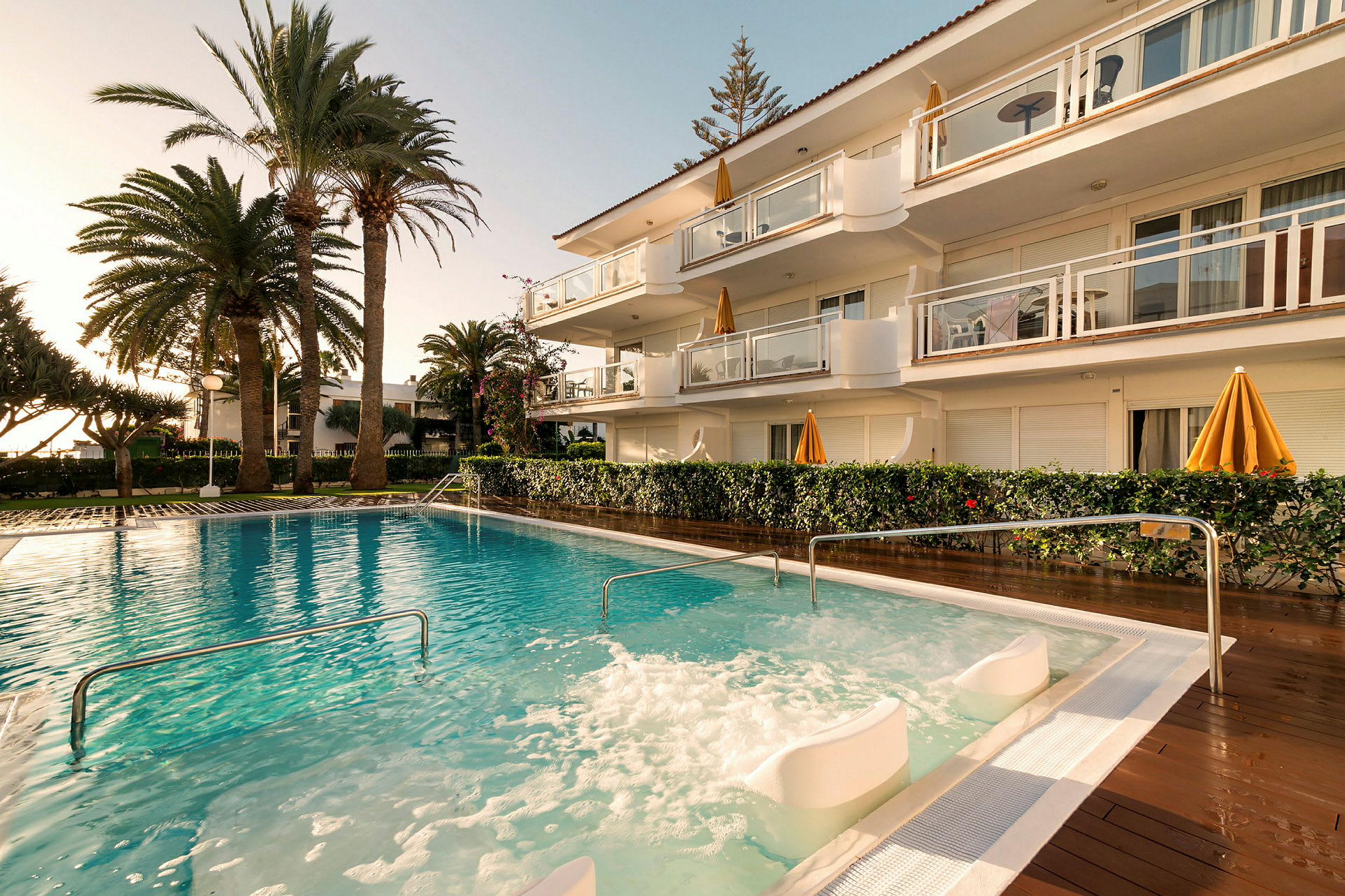 Udendørs pool med boblezone ved et hotel omgivet af palmer. (AI-genereret tekst)