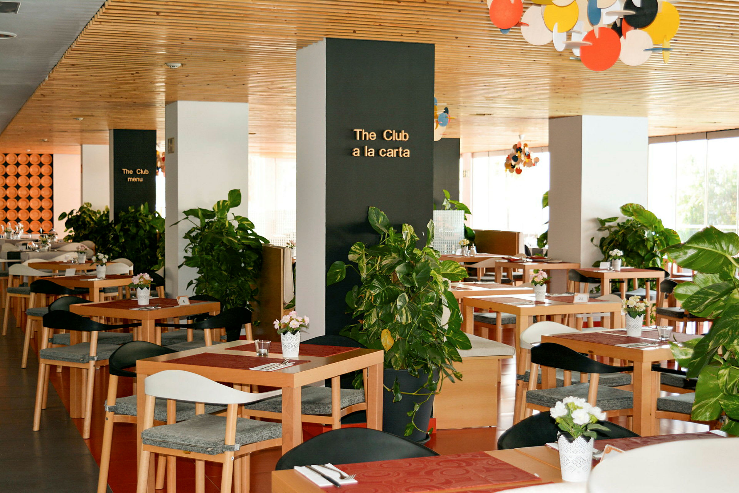 En restaurant med træborde og dekorationer med grønne planter. (AI-genereret tekst)