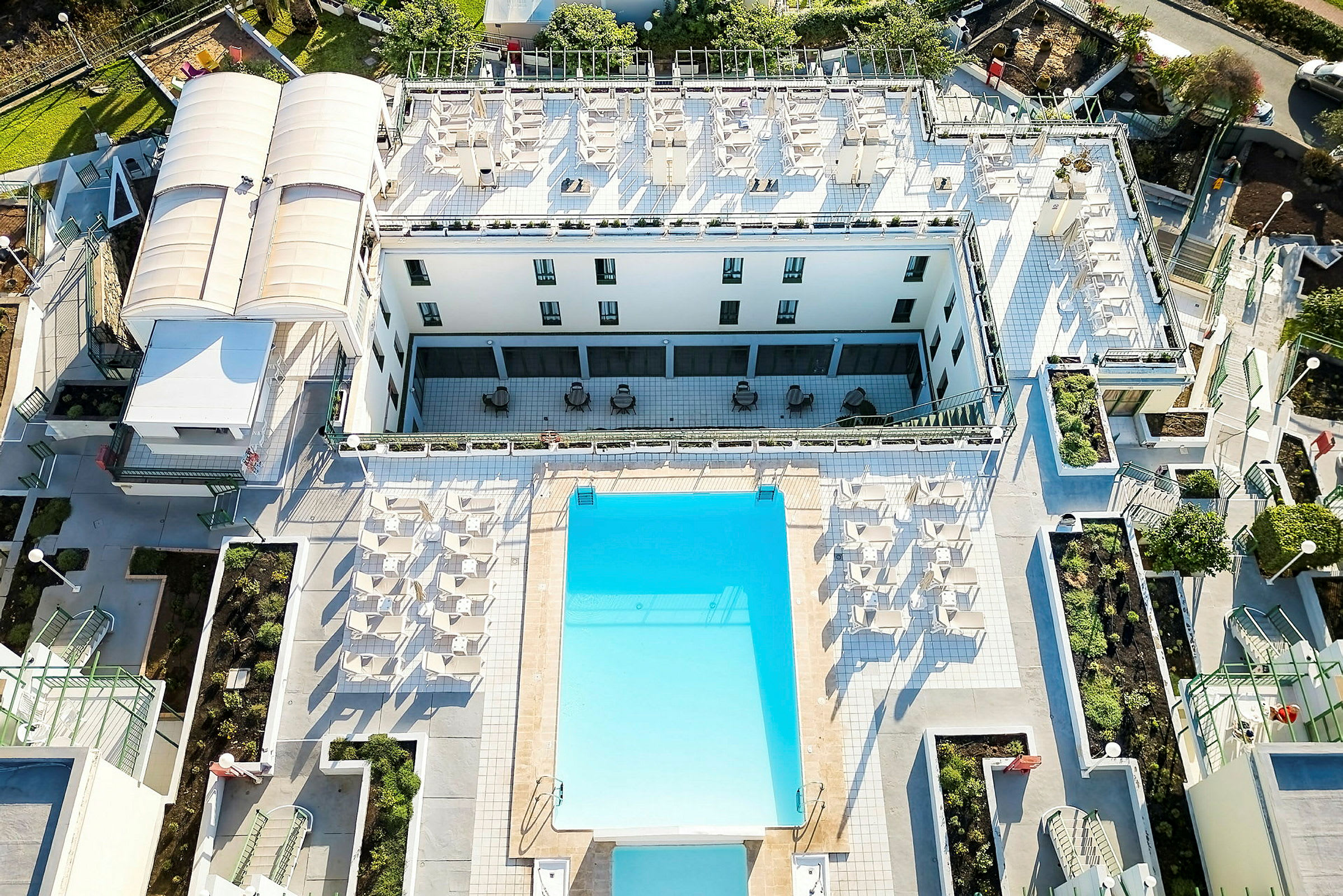 Fugleperspektiv af hotelområde med pool og liggestole. (AI-genereret tekst)