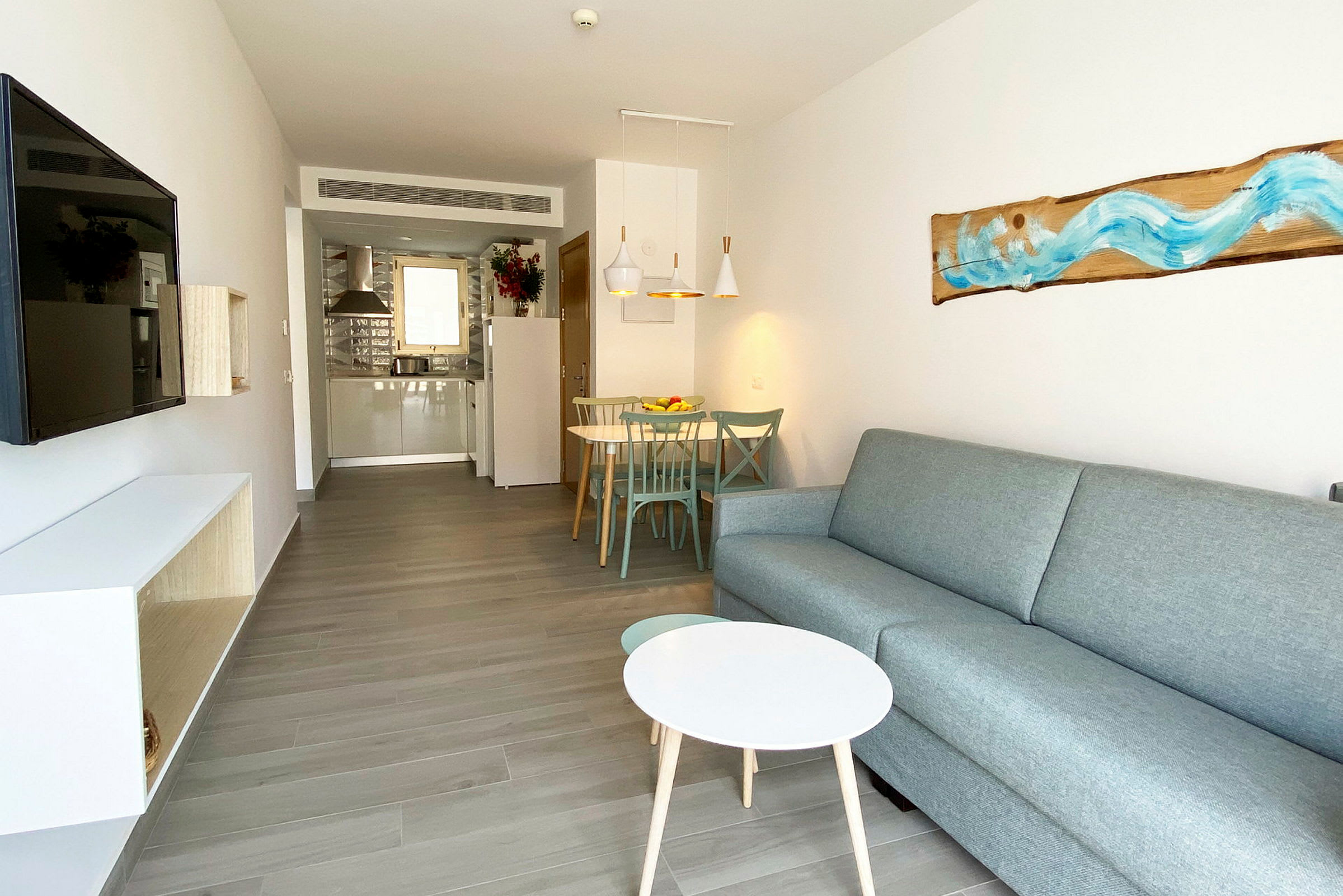 Billede af et moderne hotelværelse med sofa, sofabord, TV og spiseområde. (AI-genereret tekst)