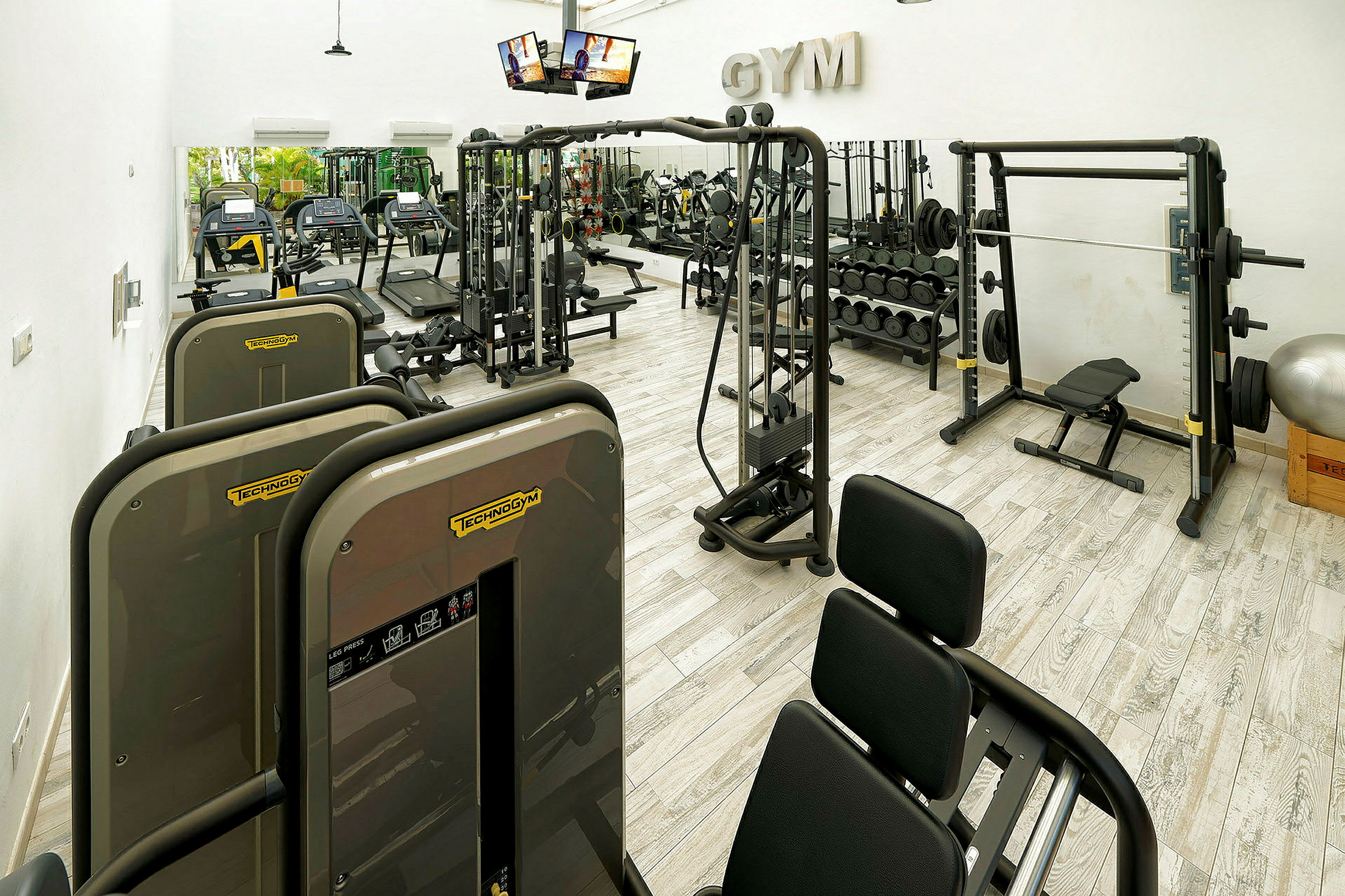 Interiør af et fitnesscenter med træningsmaskiner og vægte. (AI-genereret tekst)