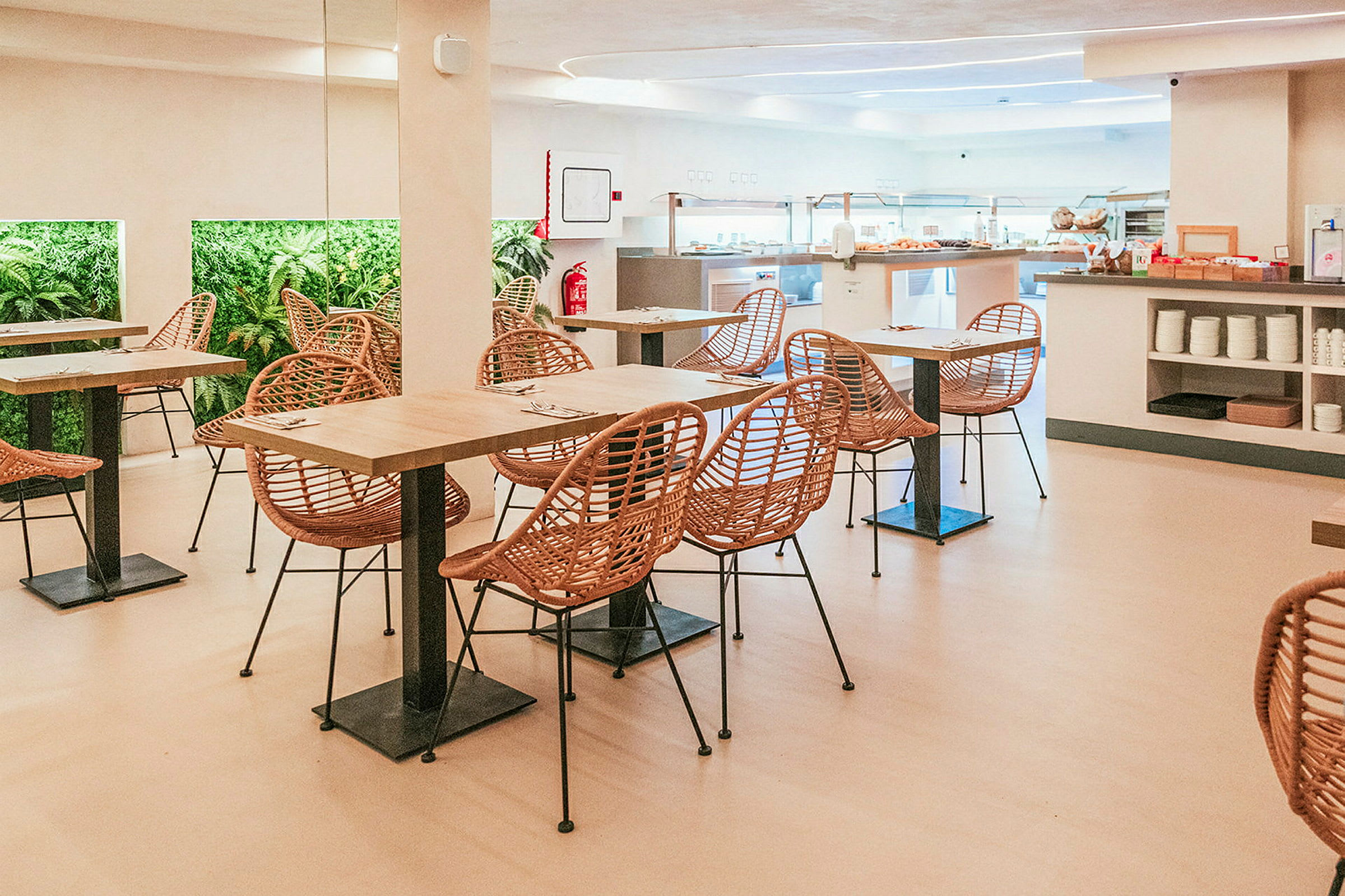 Billede af en spisesal med borde, stole og planter på væggen. (AI-genereret tekst)