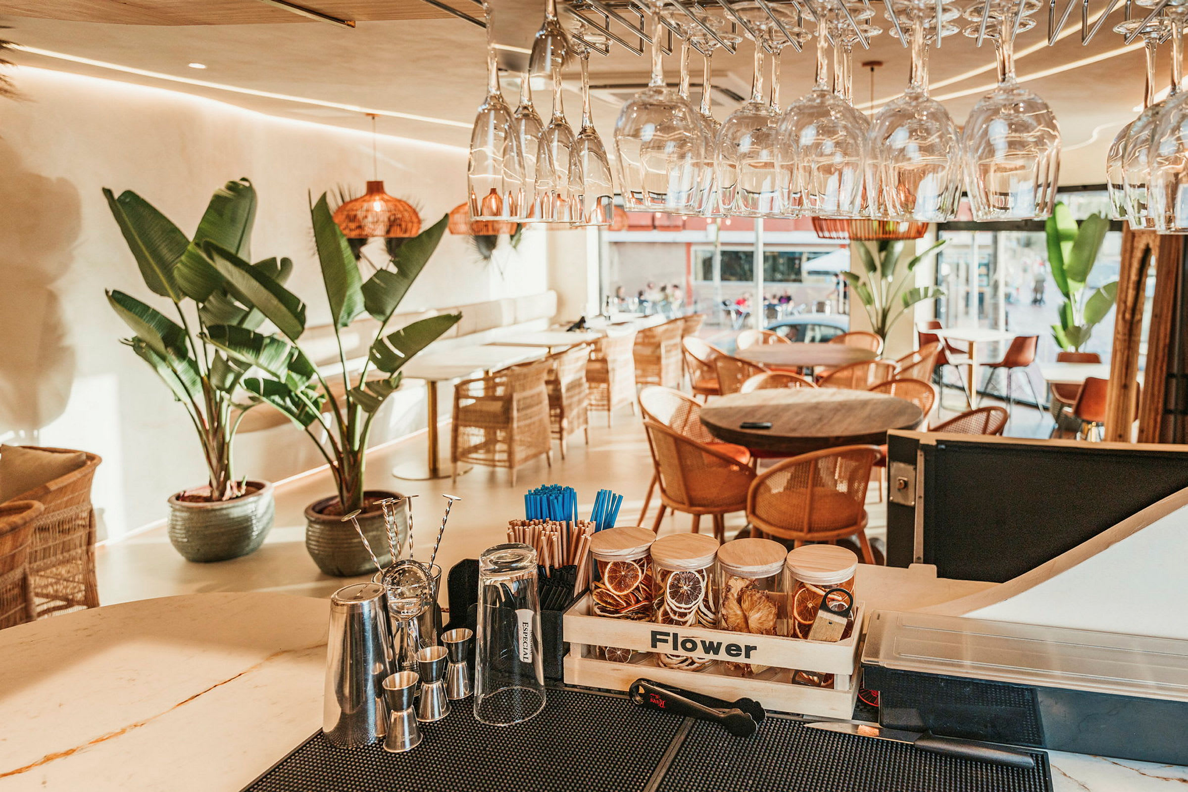 En moderne café med glas, store grønne planter og fletstole. (AI-genereret tekst)