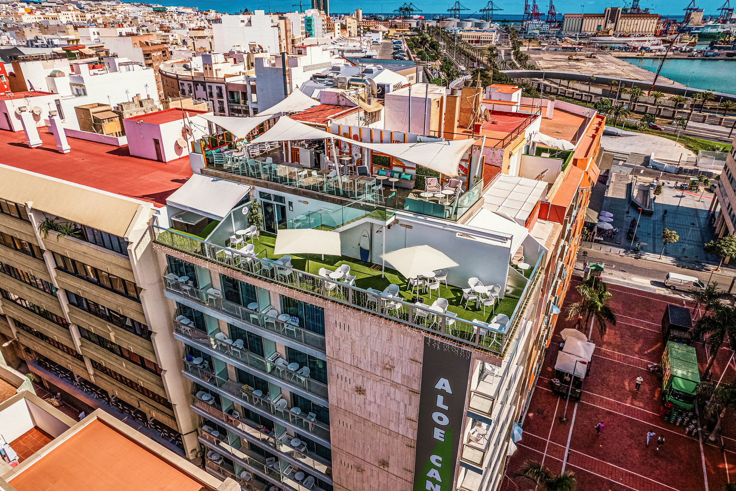 En bygning med terrasser på toppen, omgivet af en by med havet i baggrunden. (AI-genereret tekst)