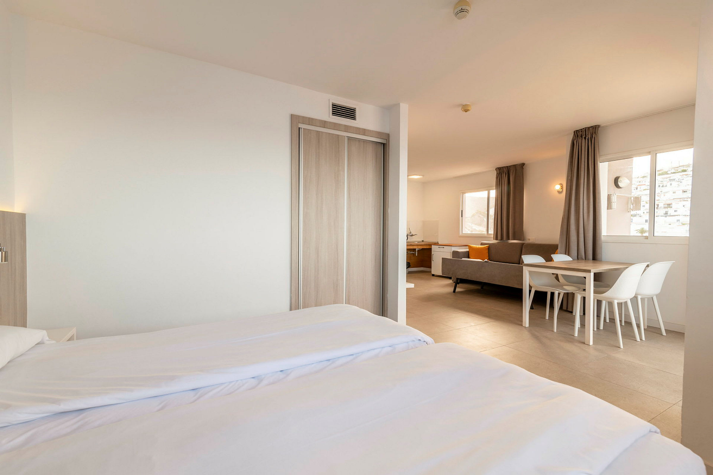 Moderne og lyst indrettet hotelværelse med dobbeltseng, siddegruppe og spisebord. (AI-genereret tekst)