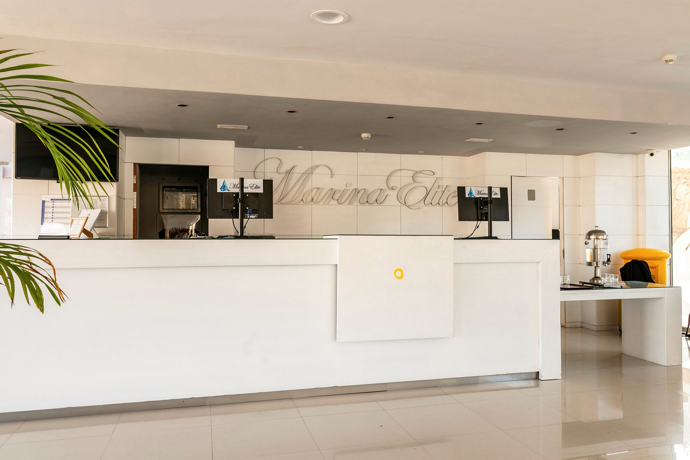 Hotellets reception med hvid skranke og computerskærme. (AI-genereret tekst)