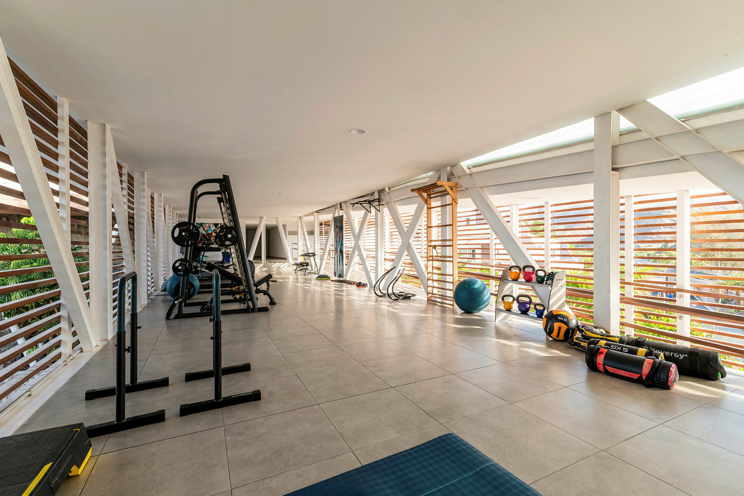 Billede af et fitnessrum med træningsudstyr, rummeligt og med meget lys. (AI-genereret tekst)