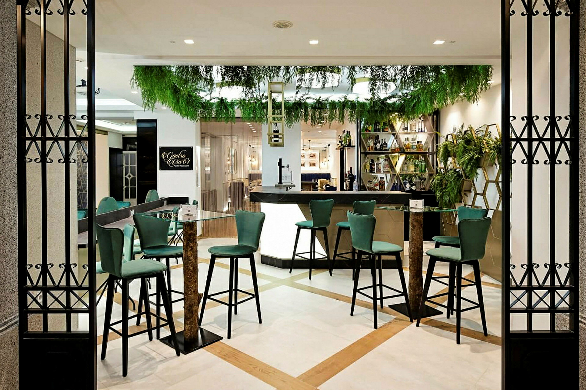 En moderne bar med grønne stole og planter som dekoration. (AI-genereret tekst)