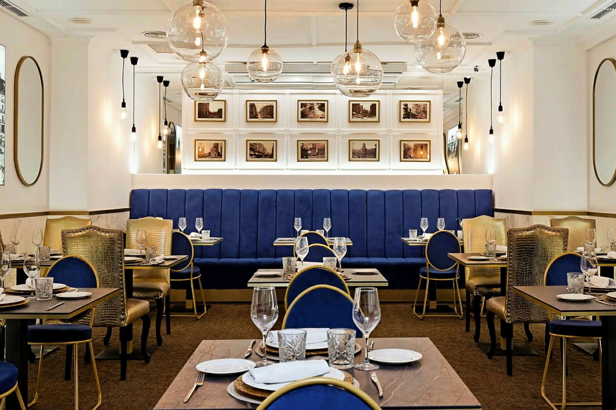 Interiør af en elegant restaurant med blå siddemøbler og gyldne detaljer. (AI-genereret tekst)