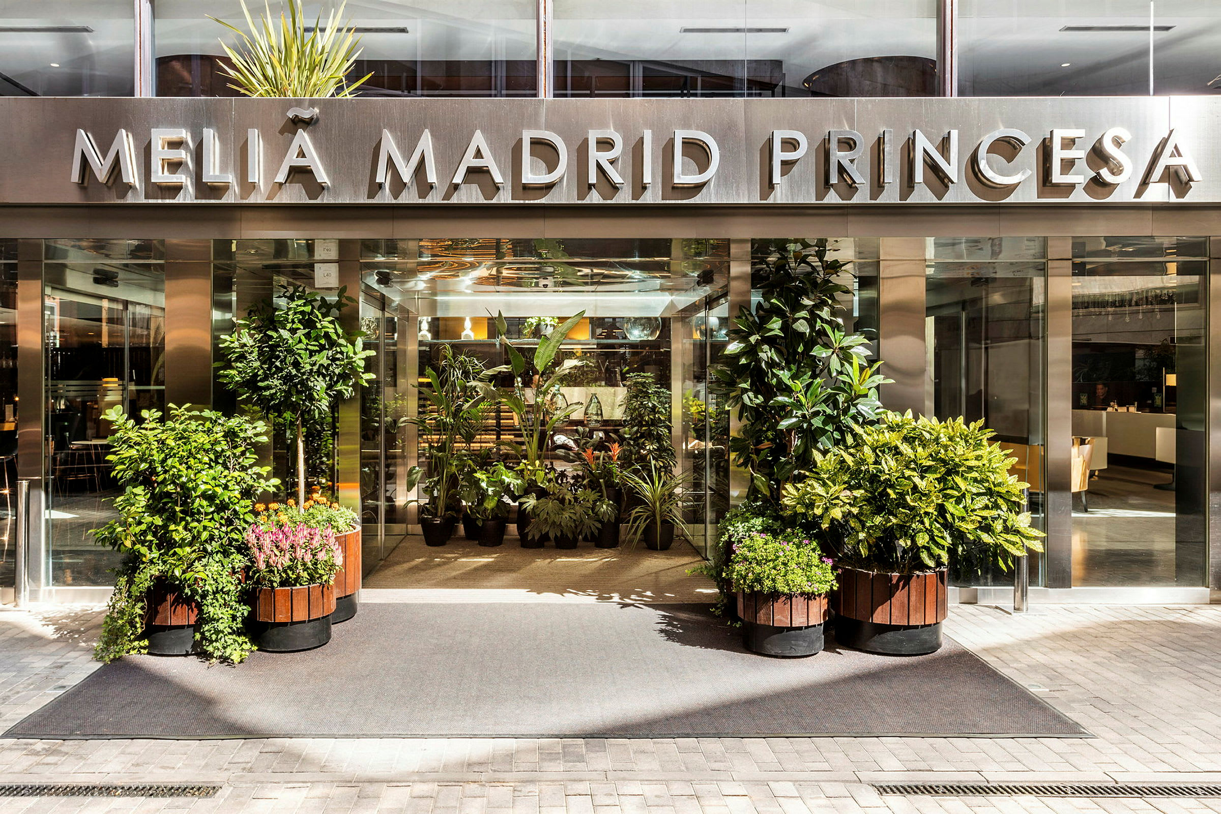 Hotelindgang med skiltet "Meliá Madrid Princesa" og omkringliggende planter. (AI-genereret tekst)