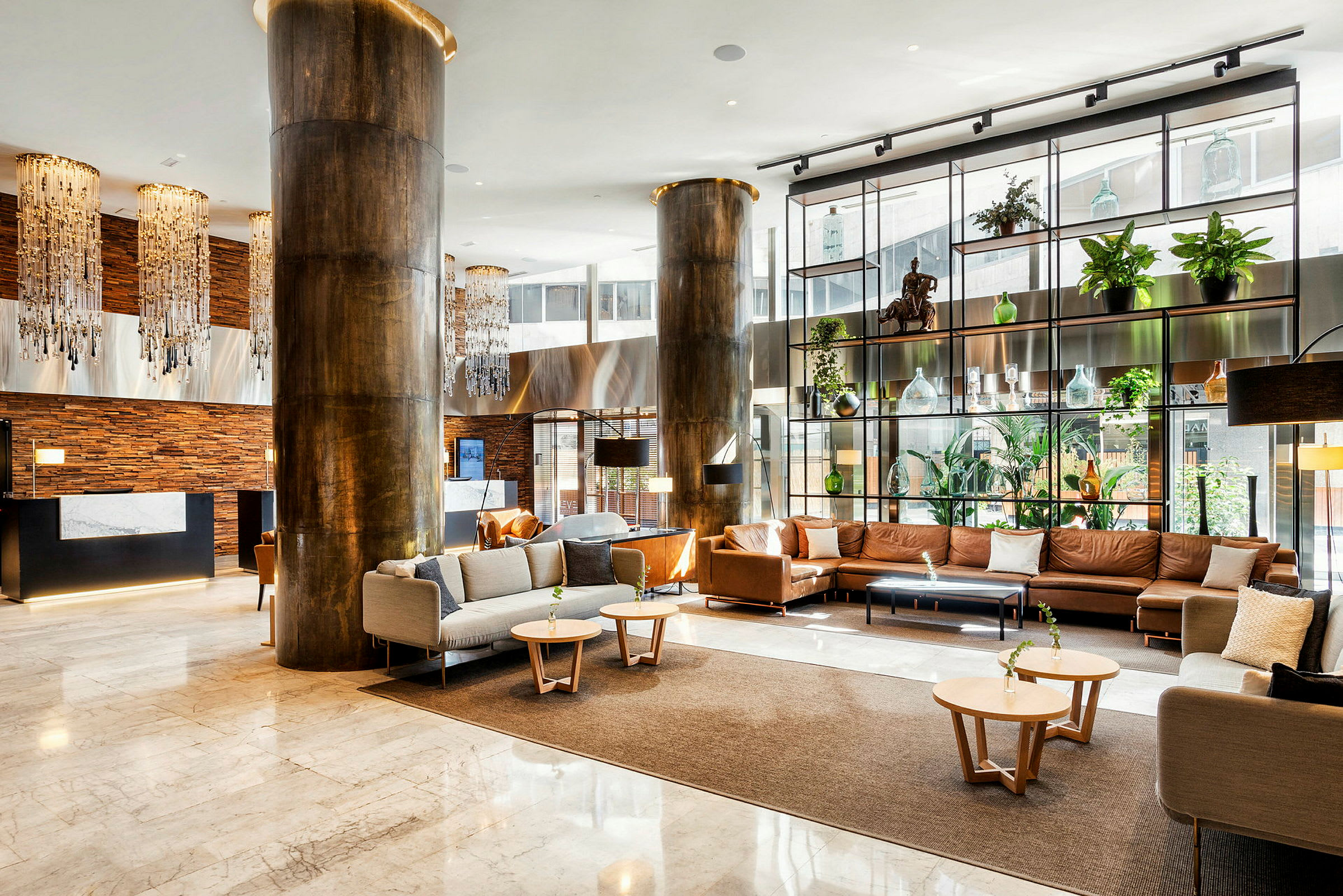 En moderne hotellobby med luksuriøst interiør, herunder sofaer og lænestole, dekorationer, planter og belysning. (AI-genereret tekst)