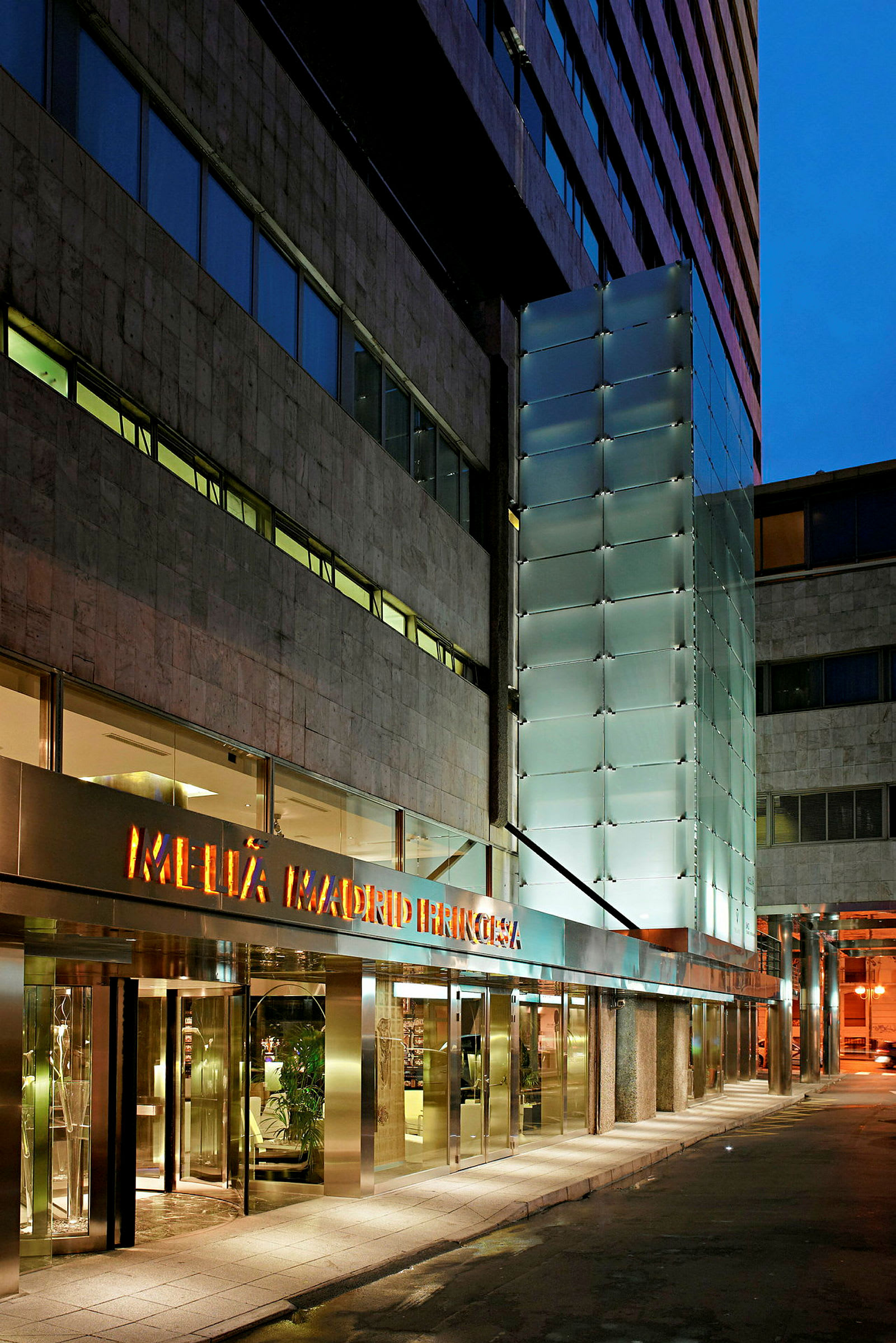 Indgangen til et hotel med glas- og marmorfacade. (AI-genereret tekst)