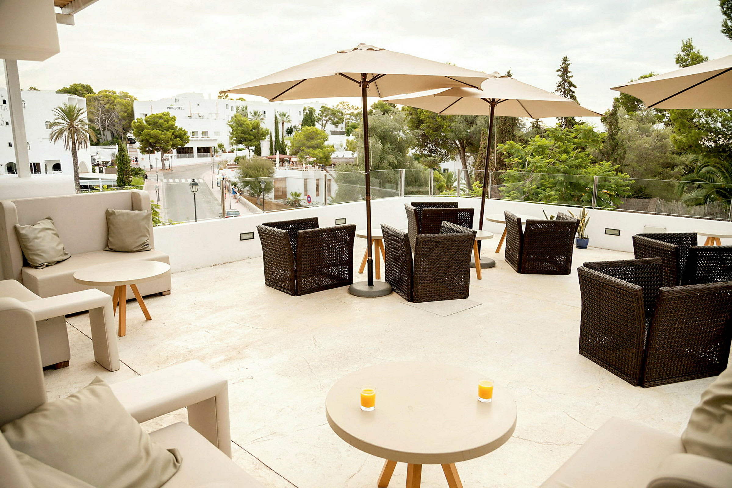 Terrasse med siddepladser og parasoller, udsigt over grøntområde og bygninger. (AI-genereret tekst)