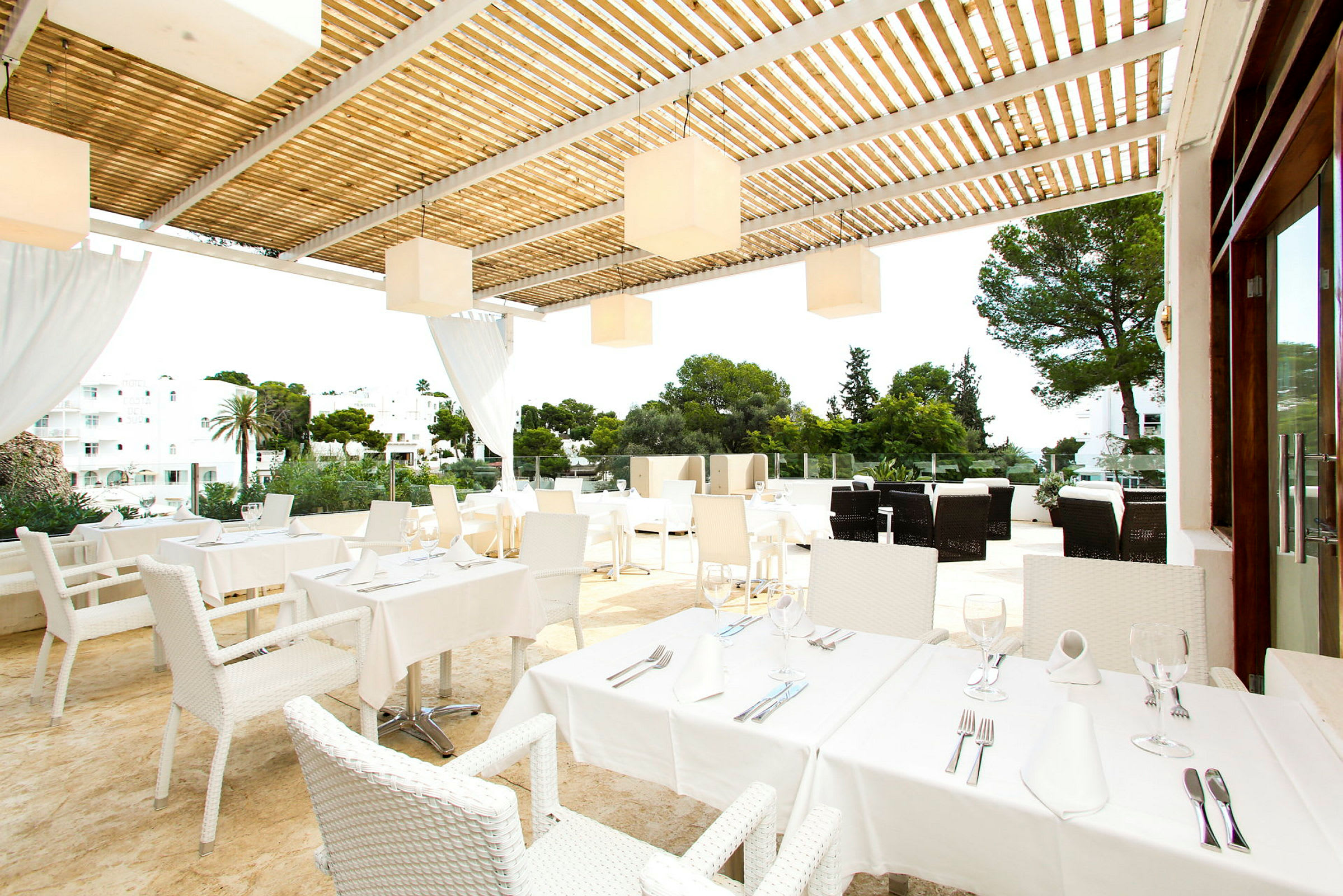 En terrasse med borde og stole, dækket til måltid, under en pergola. (AI-genereret tekst)