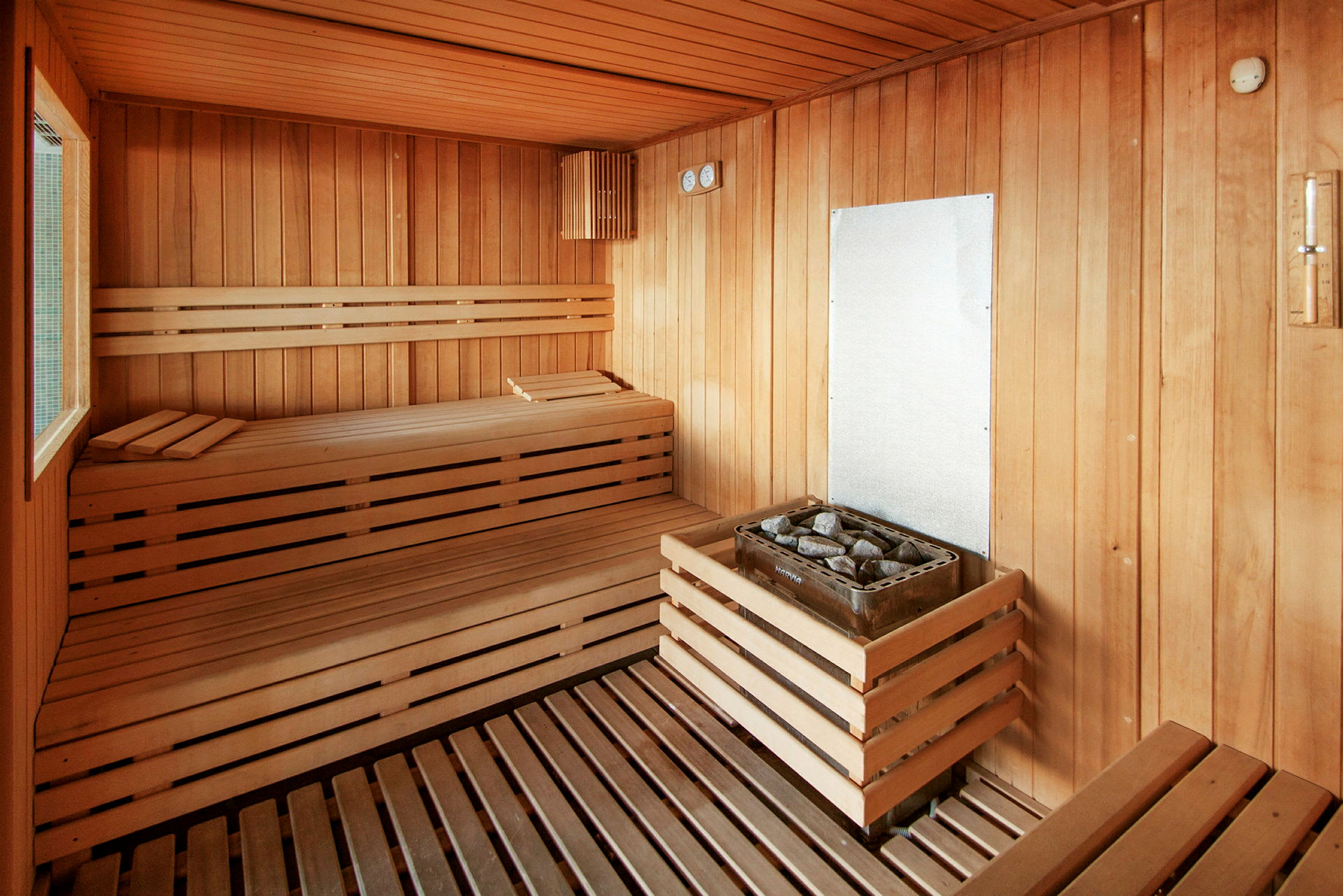 En traditionel sauna med træpaneler, siddebænke og en saunaovn med sten. (AI-genereret tekst)