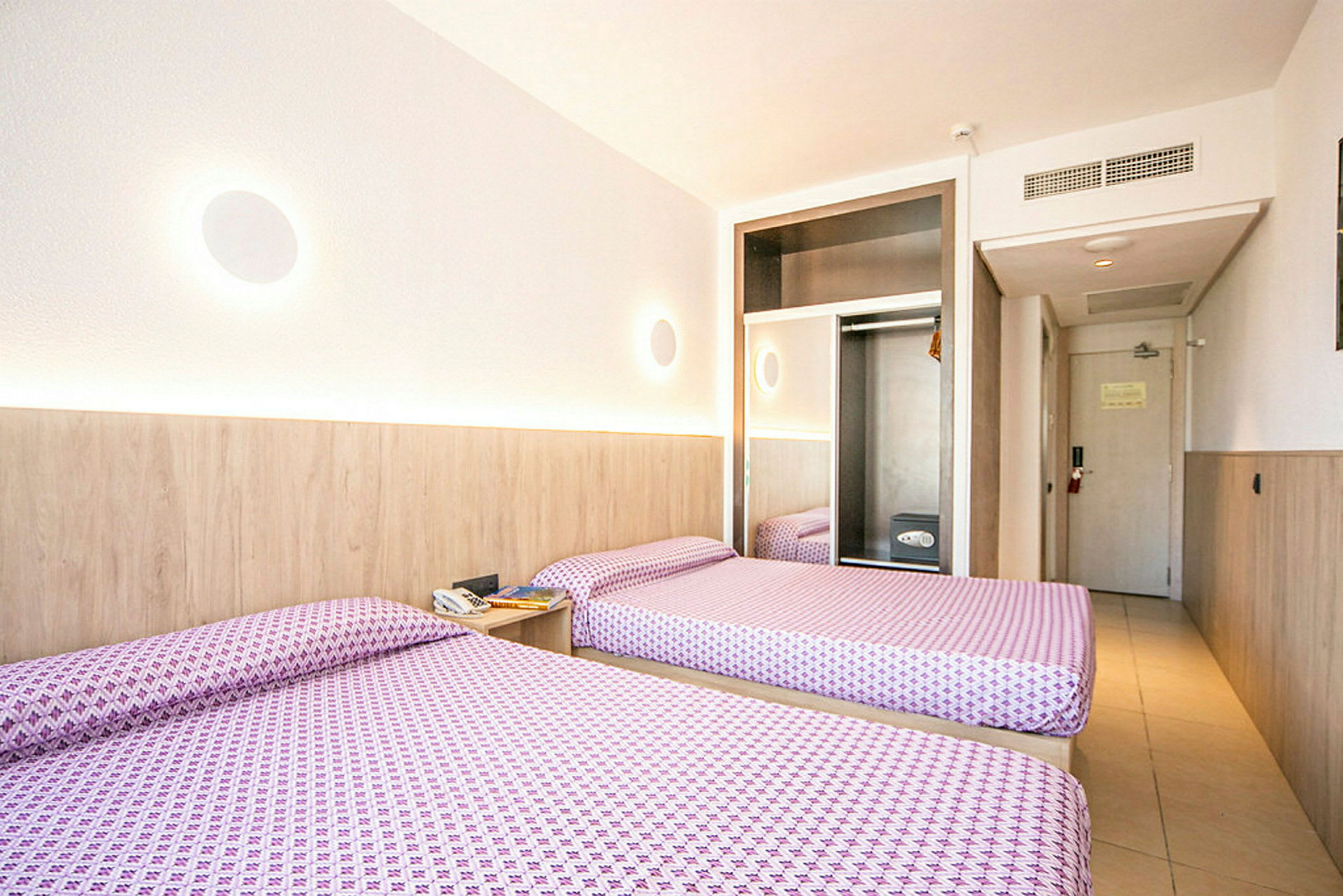 Hotelværelse med to enkeltsenge, garderobe og dør. (AI-genereret tekst)