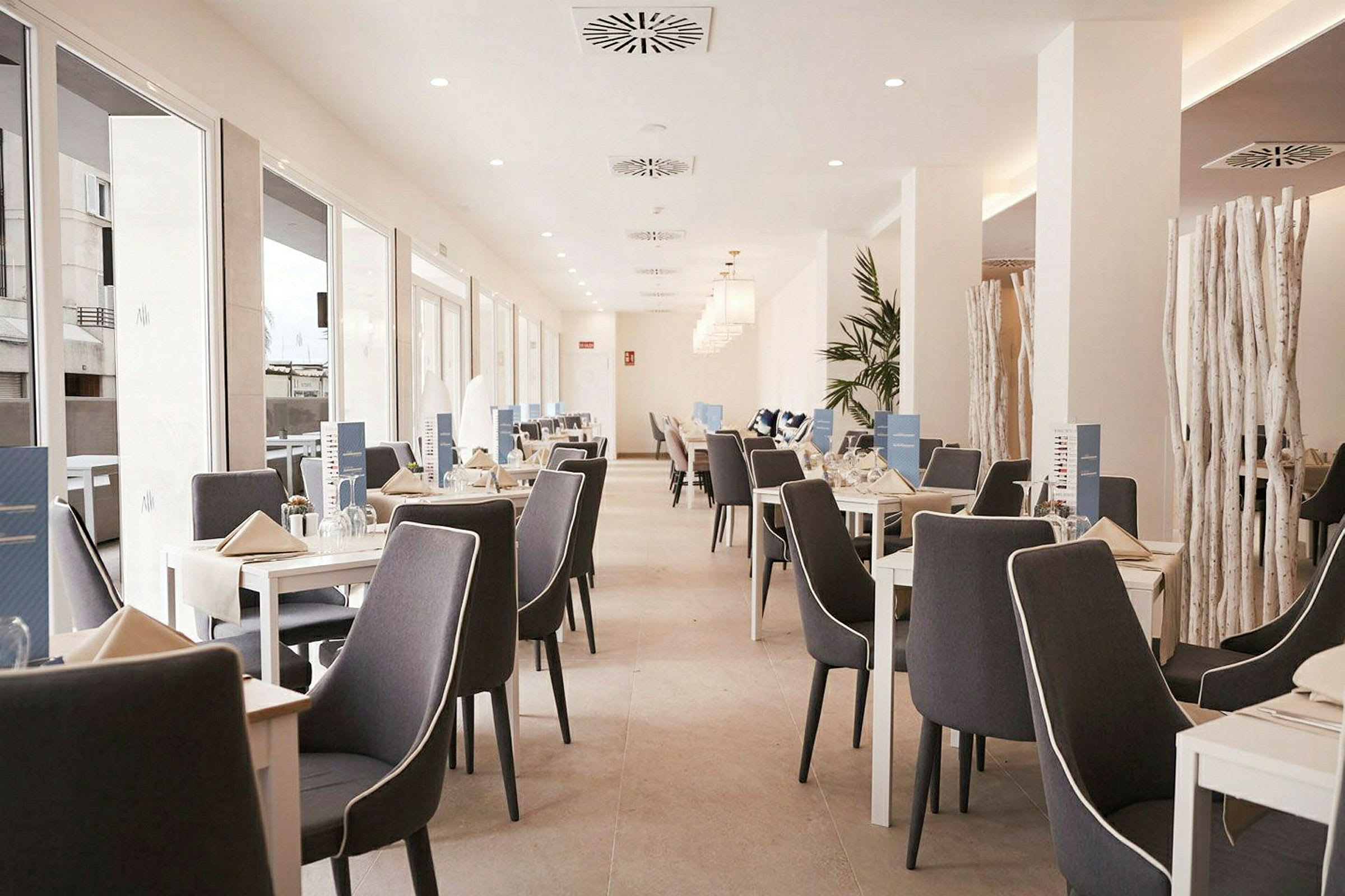 En lys restaurant med oppstillede borde og stole. (AI-genereret tekst)