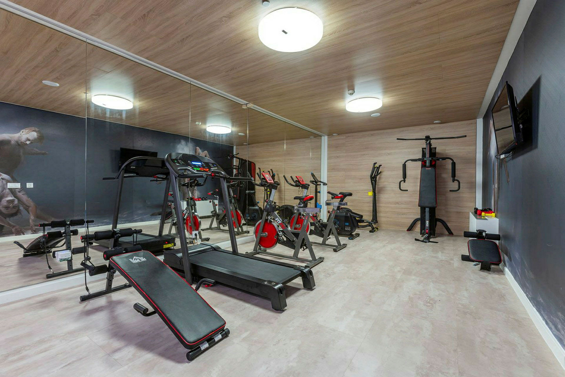 Billede af et fitnesscenter med træningsudstyr, herunder løbebånd, motionscykler og andet udstyr. (AI-genereret tekst)