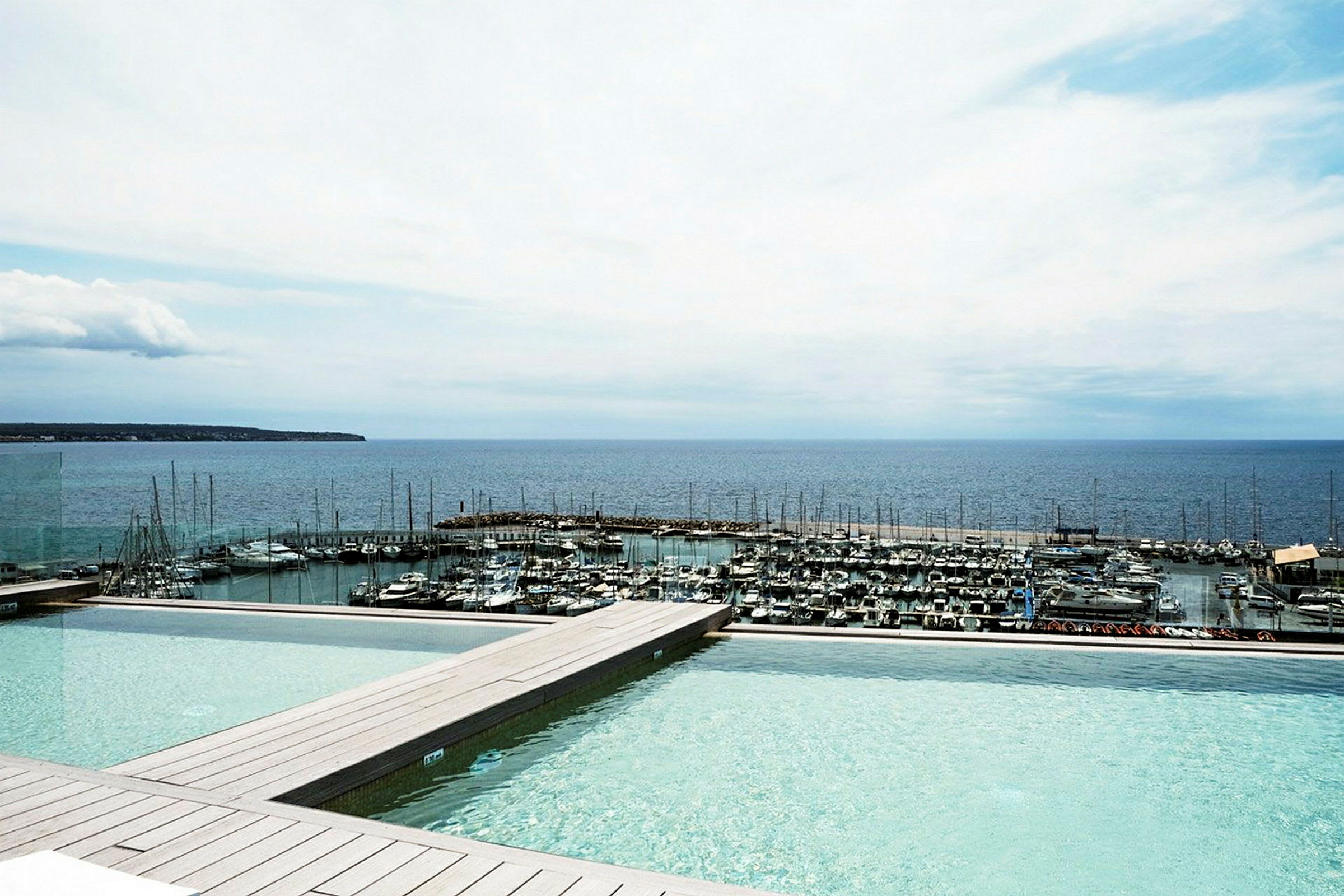 Billede af en infinitypool med udsigt til en lystbådehavn og havet. (AI-genereret tekst)