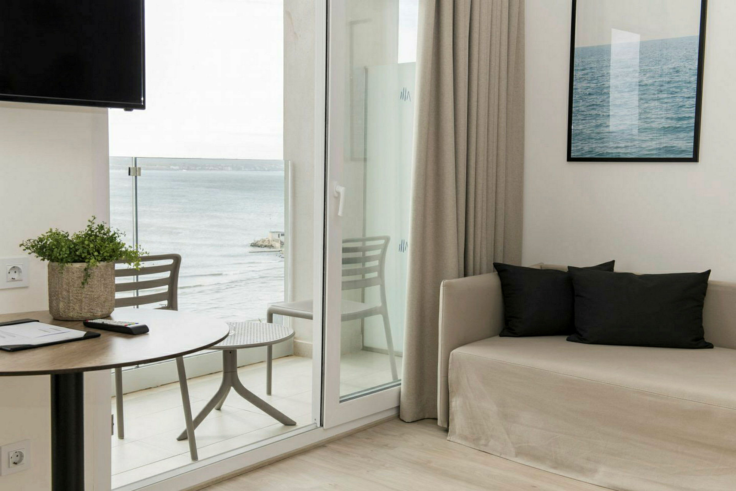 Et rum med sofa, bord og udsigt til havet. (AI-genereret tekst)