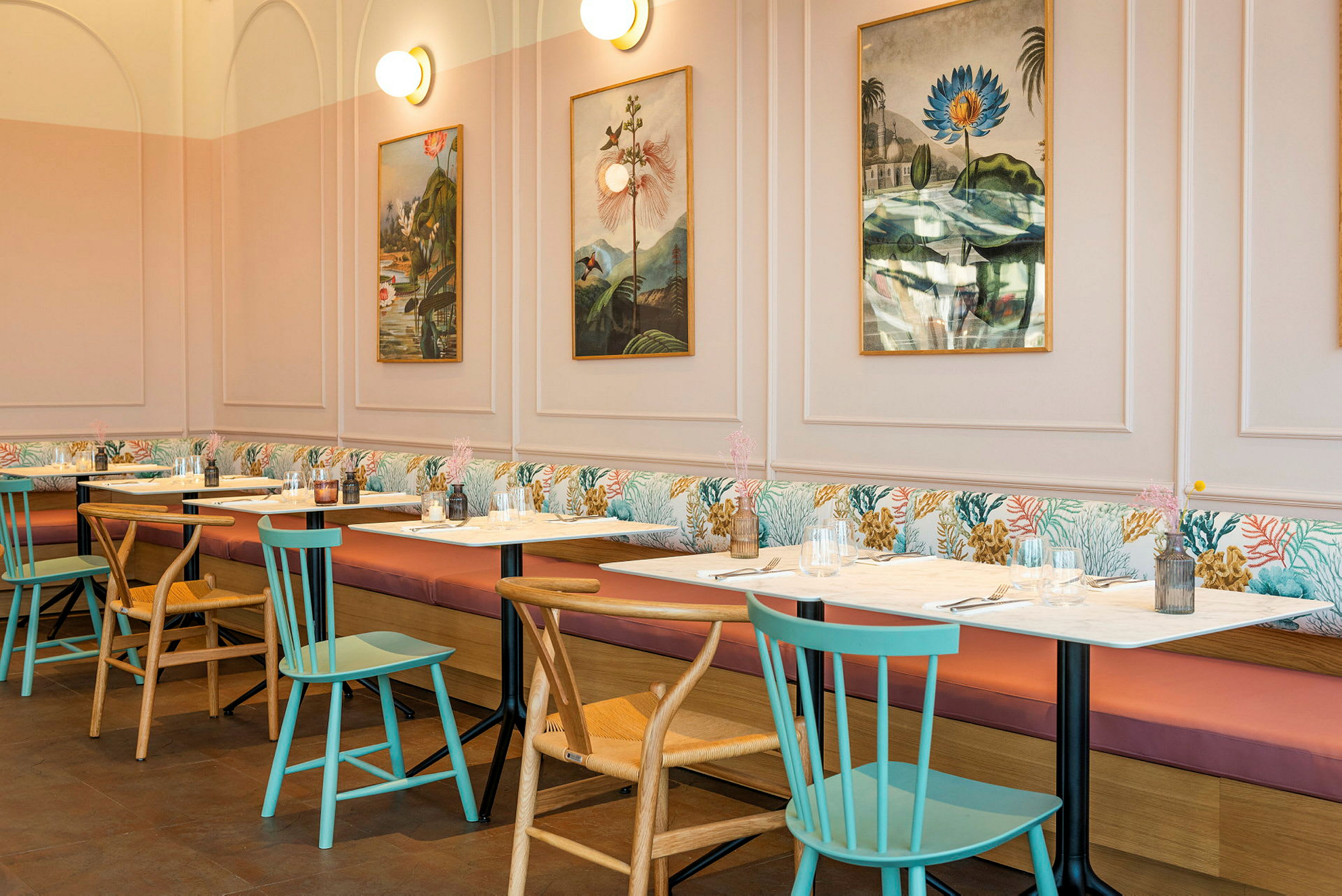 En restaurant med borde og stole, billeder på væggen og bløde sofaer langs væggen. (AI-genereret tekst)