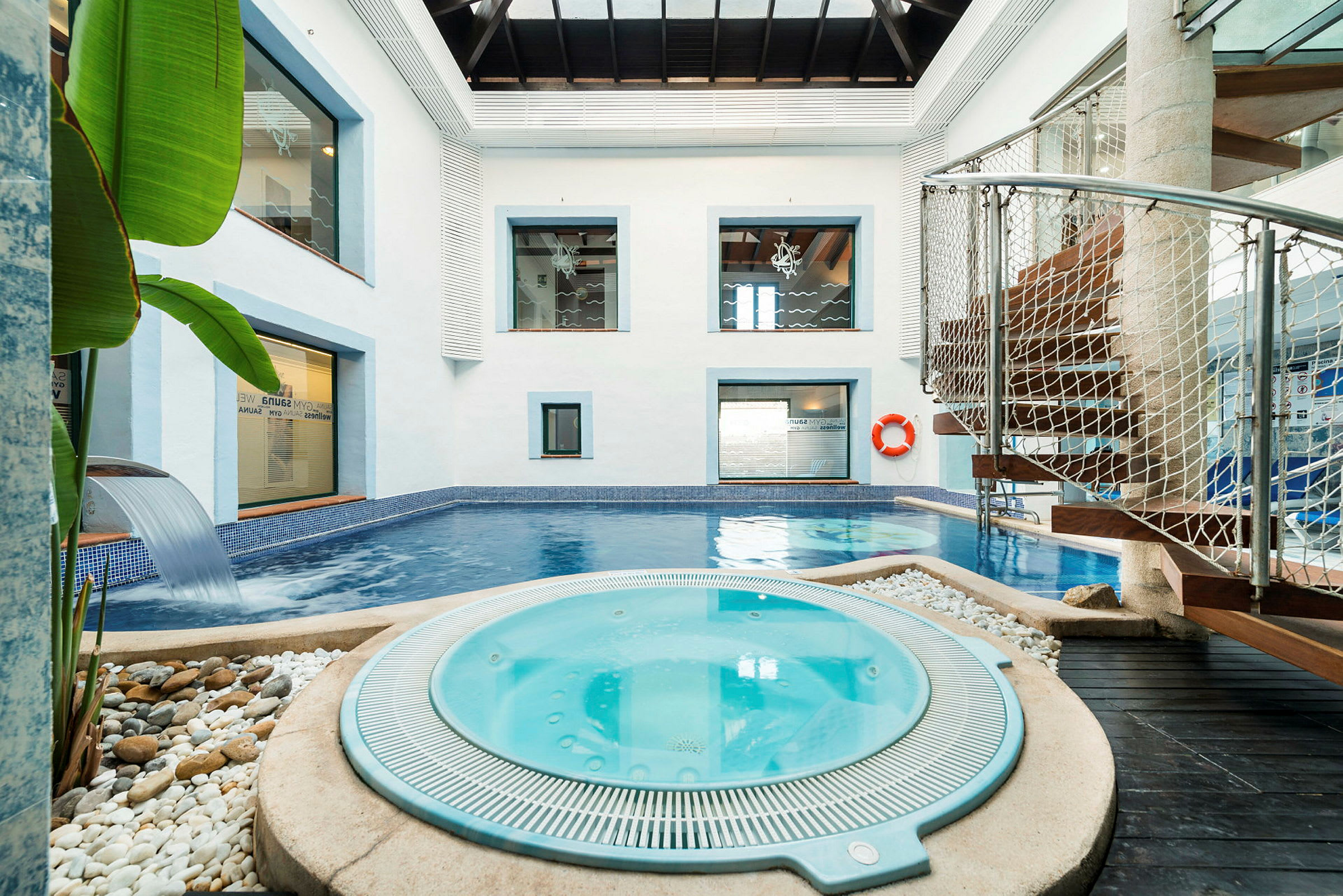Indendørs spa med en pool og jacuzzi omgivet af moderne detaljer. (AI-genereret tekst)