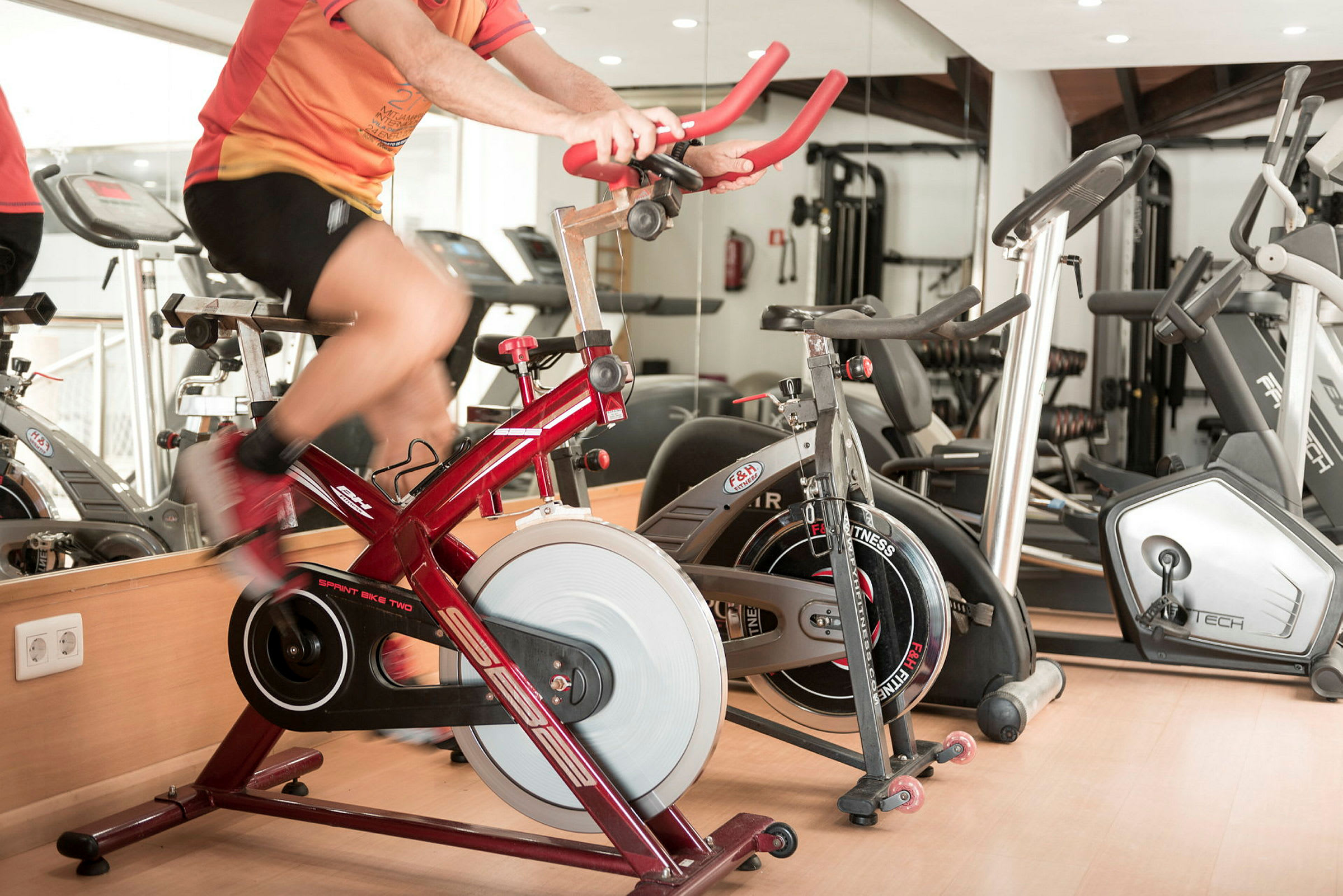 Personen træner på en rød motionscykel i et fitnesscenter. (AI-genereret tekst)