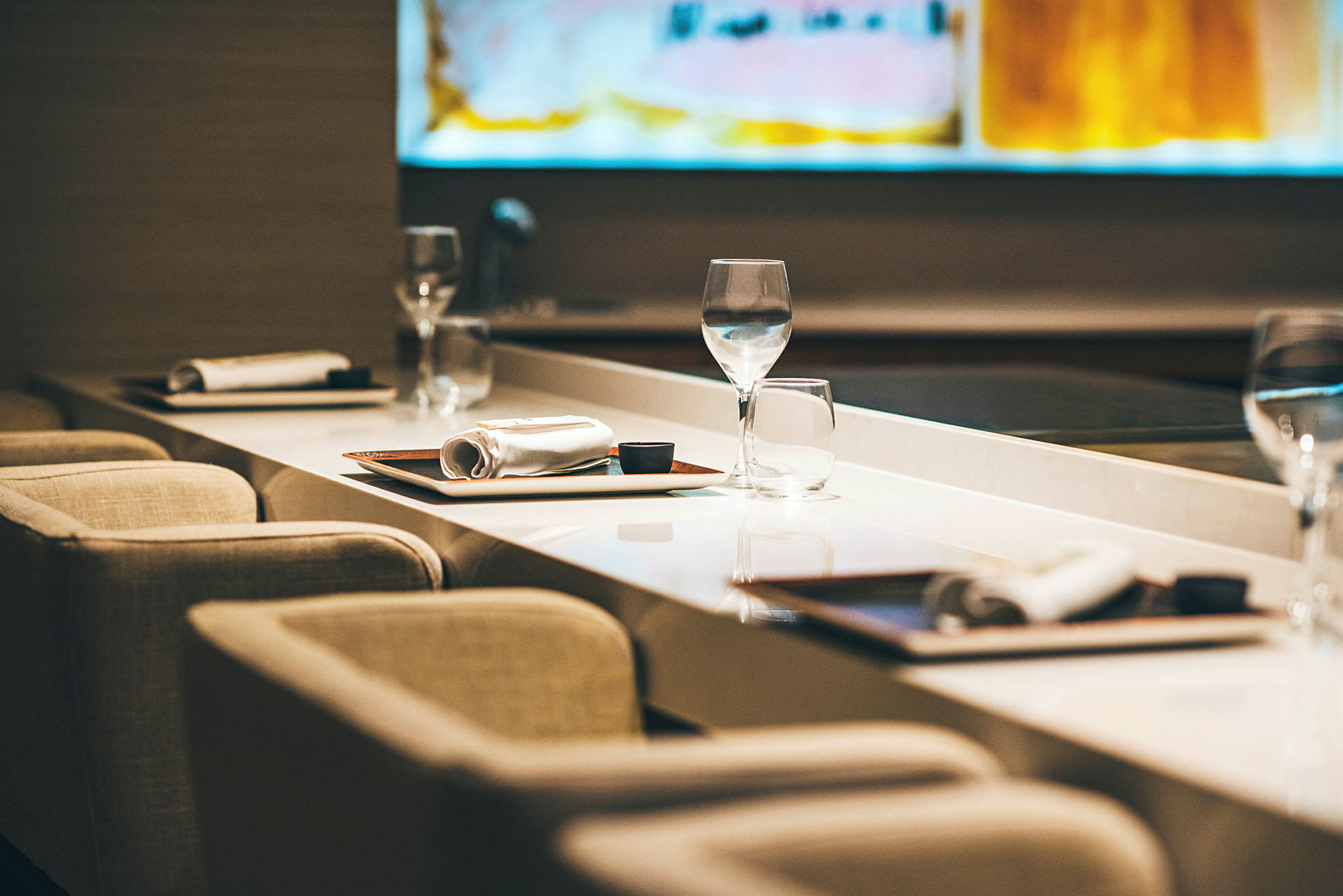En række af borde, dækket med glas, tallerkener og servietter, i en afslappet restaurantstemning. (AI-genereret tekst)