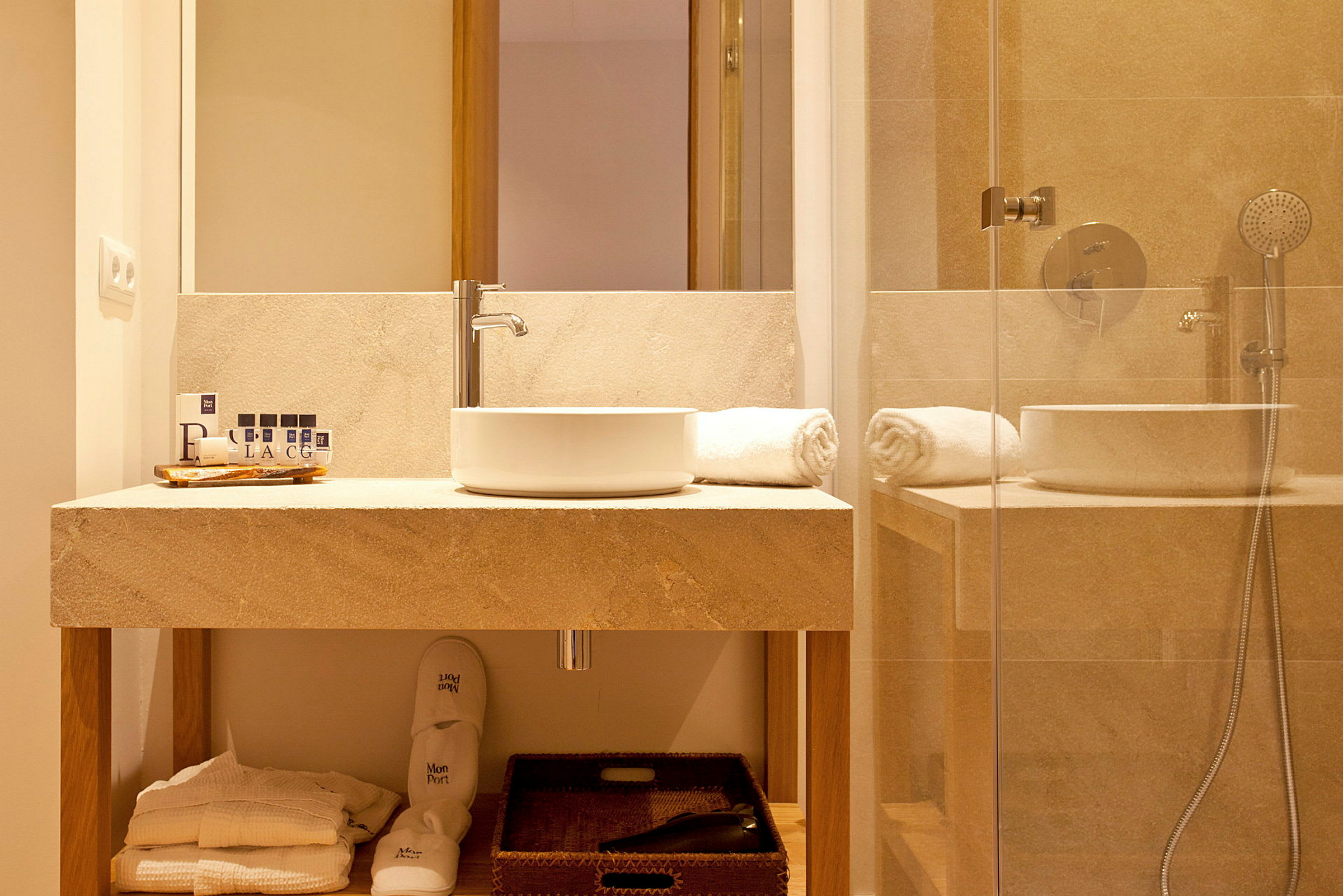 Et badeværelse med en moderne håndvask, spejl og brusebad. Håndklæder og toiletartikler er placeret på bordet. (AI-genereret tekst)