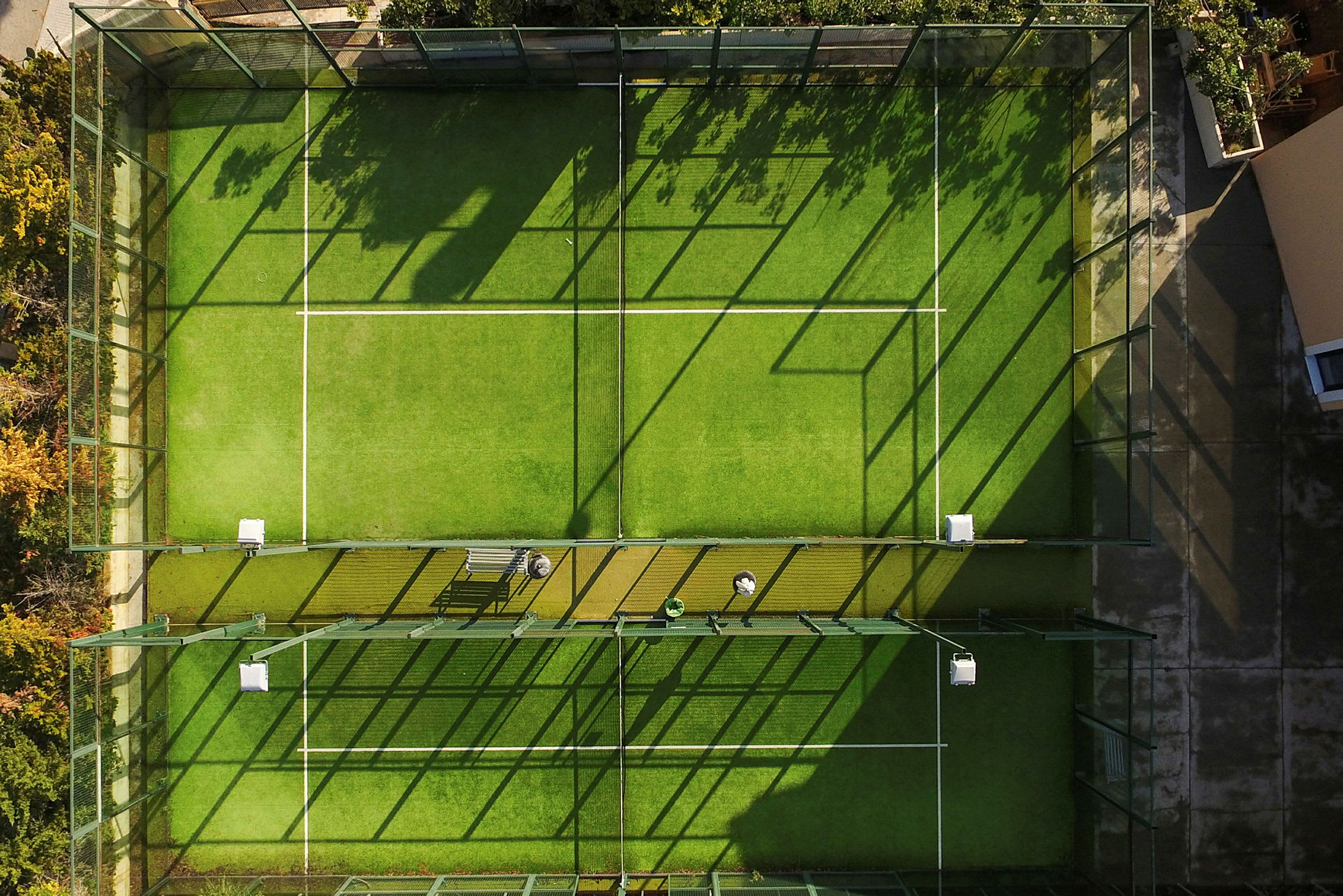 Luftfoto af en indhegnet padelbane med grøn kunstgræsoverflade. (AI-genereret tekst)