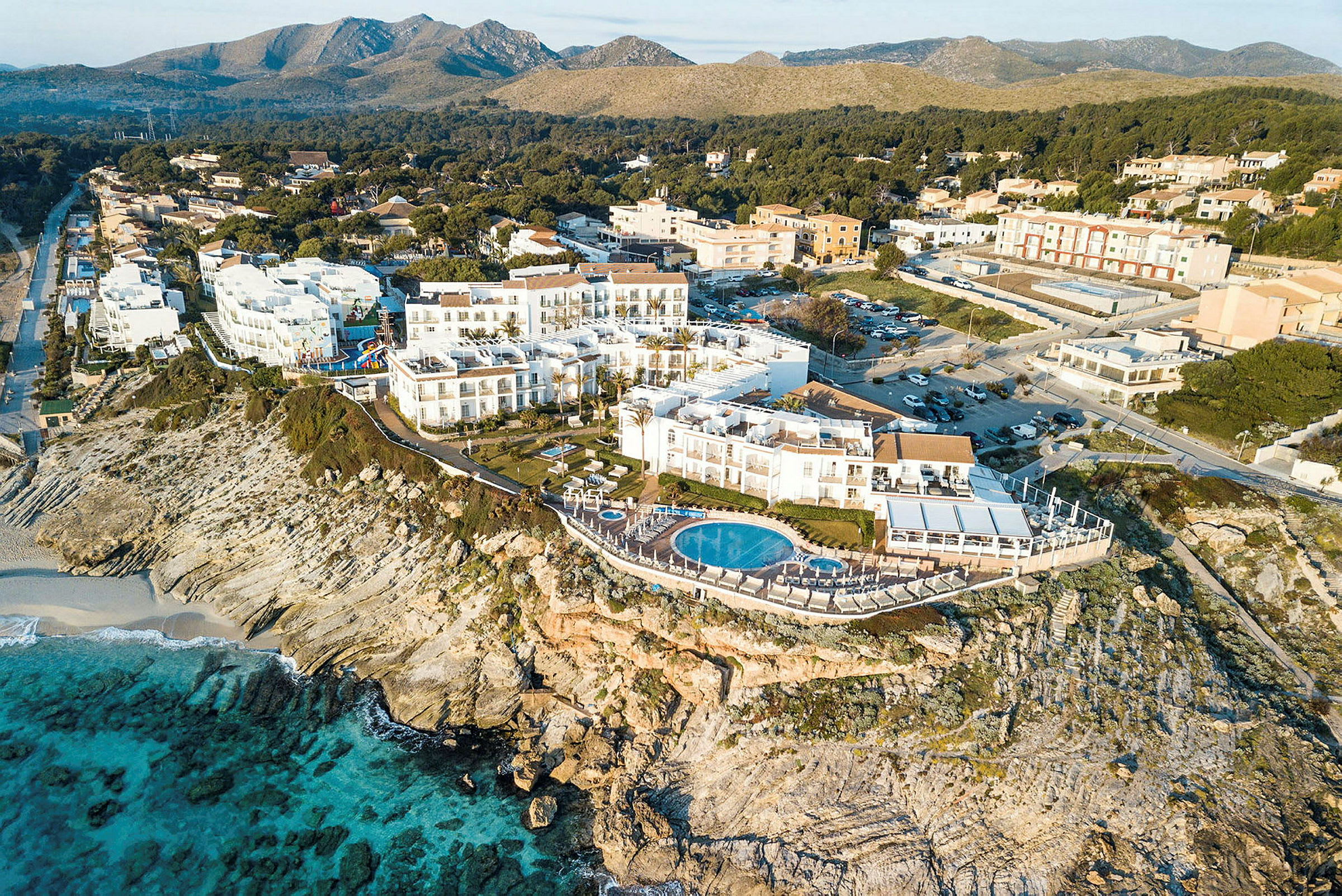 Luftfoto af et hotel på en klippe med pool og udsigt over havet. (AI-genereret tekst)