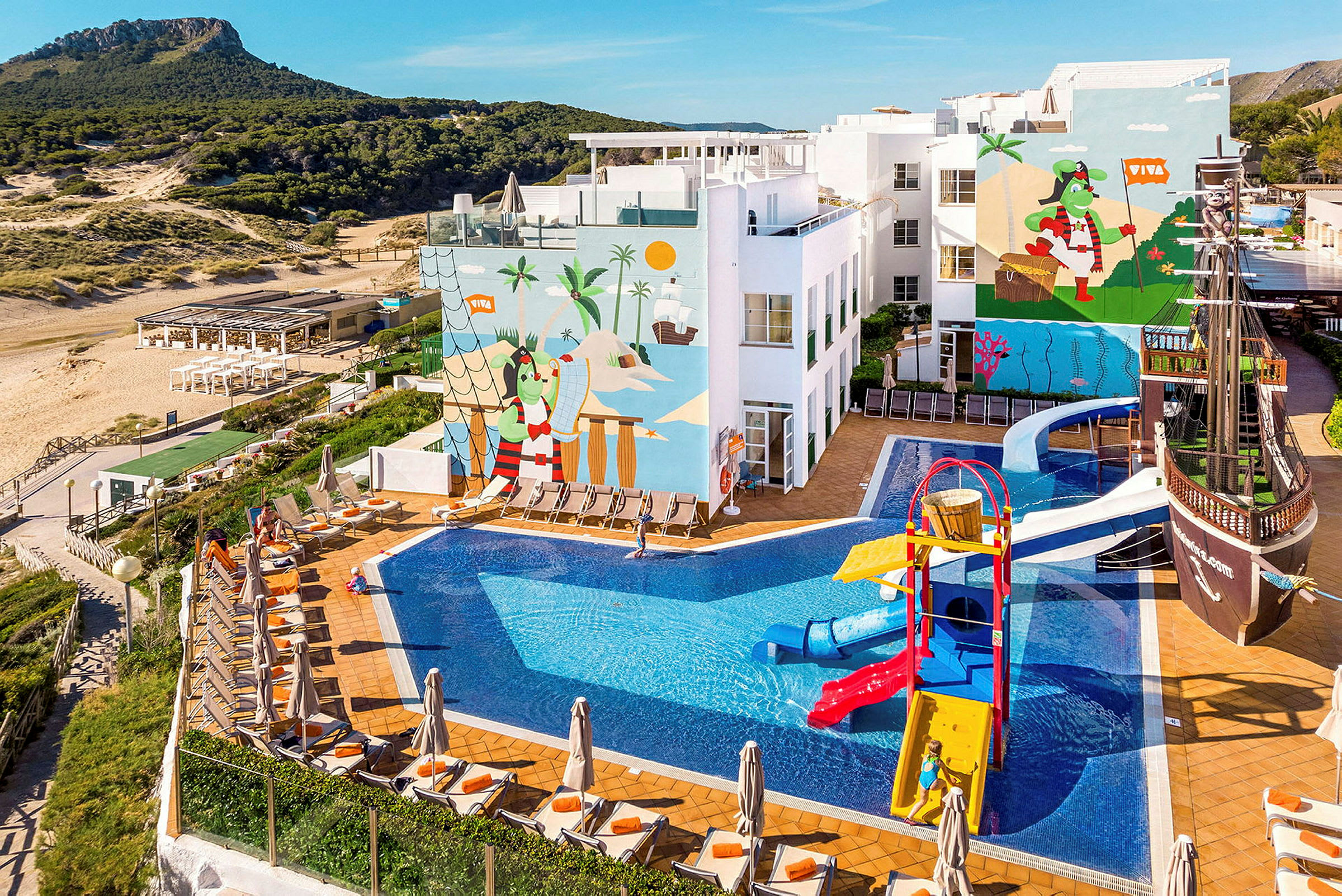 En udendørs swimmingpool ved et hotel med legeplads og nærliggende strand. (AI-genereret tekst)