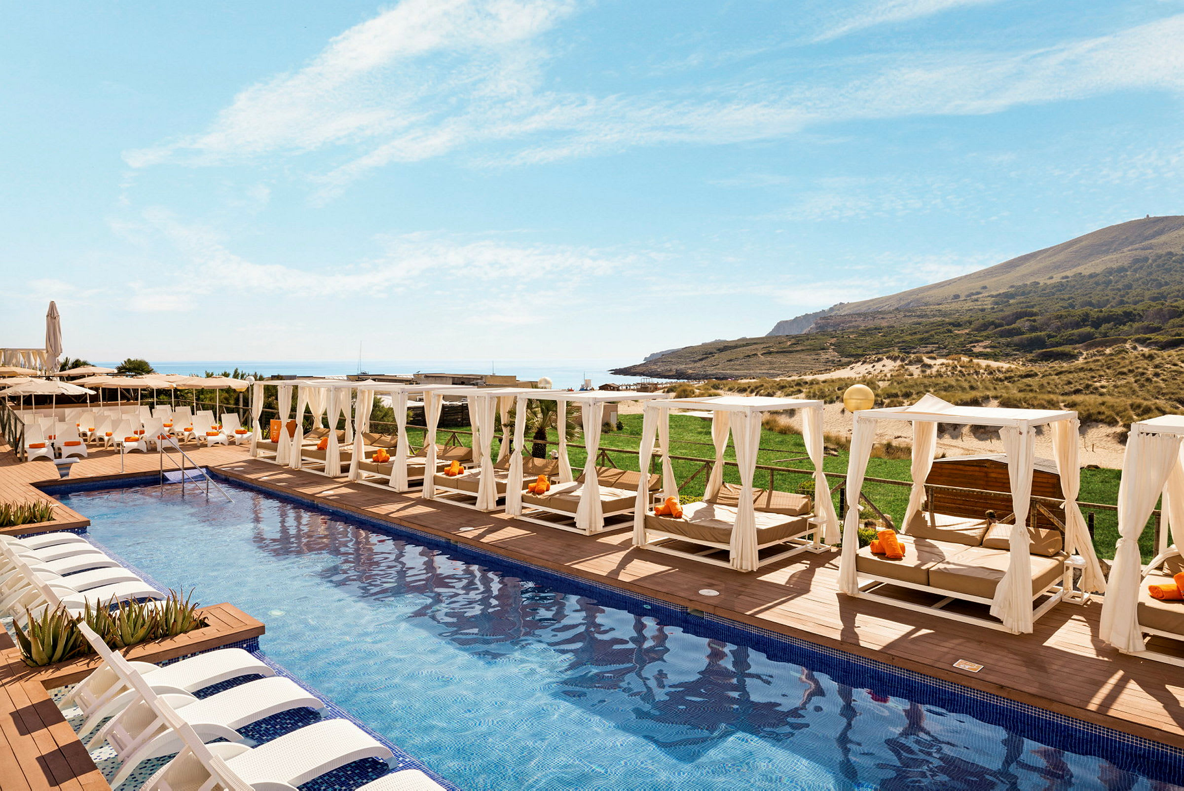 Dekorative liggestole og skyggende senge omkring en moderne pool på et hotel tæt på stranden. (AI-genereret tekst)