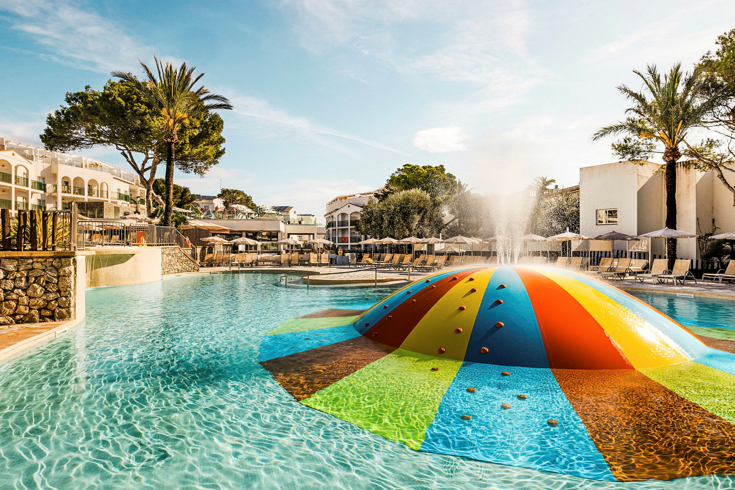 Et farverigt legetøj er placeret i en udendørs pool på et hotelområde. (AI-genereret tekst)