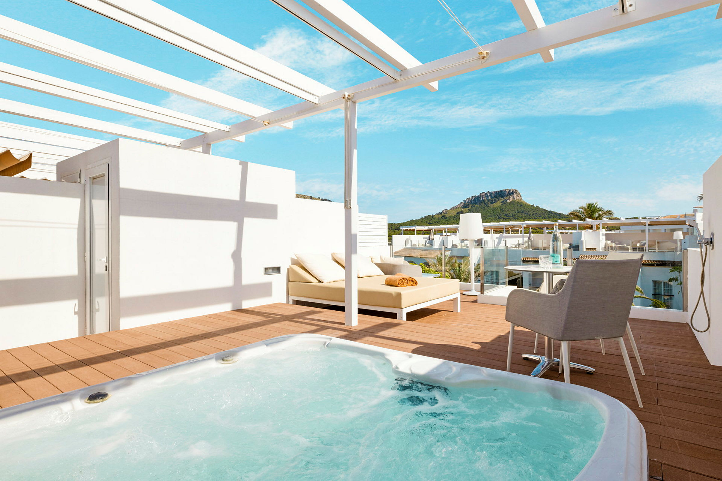 Terrasse med jacuzzi, solseng og udsigt til grønne bjerge. (AI-genereret tekst)