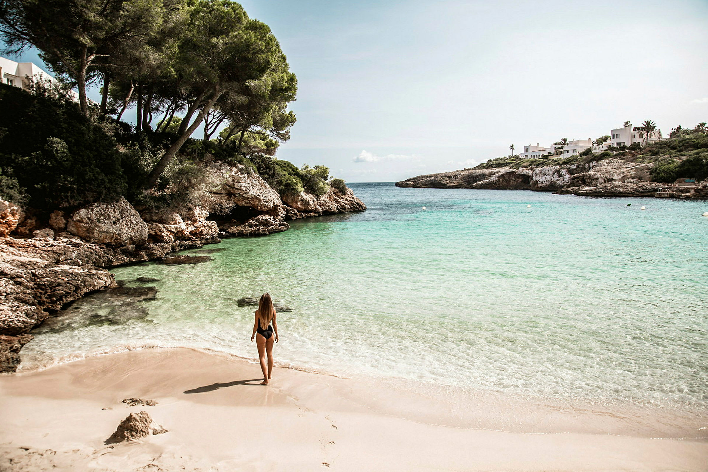 Kvinde på en sandstrand ved klart turkis hav. (AI-genereret tekst)