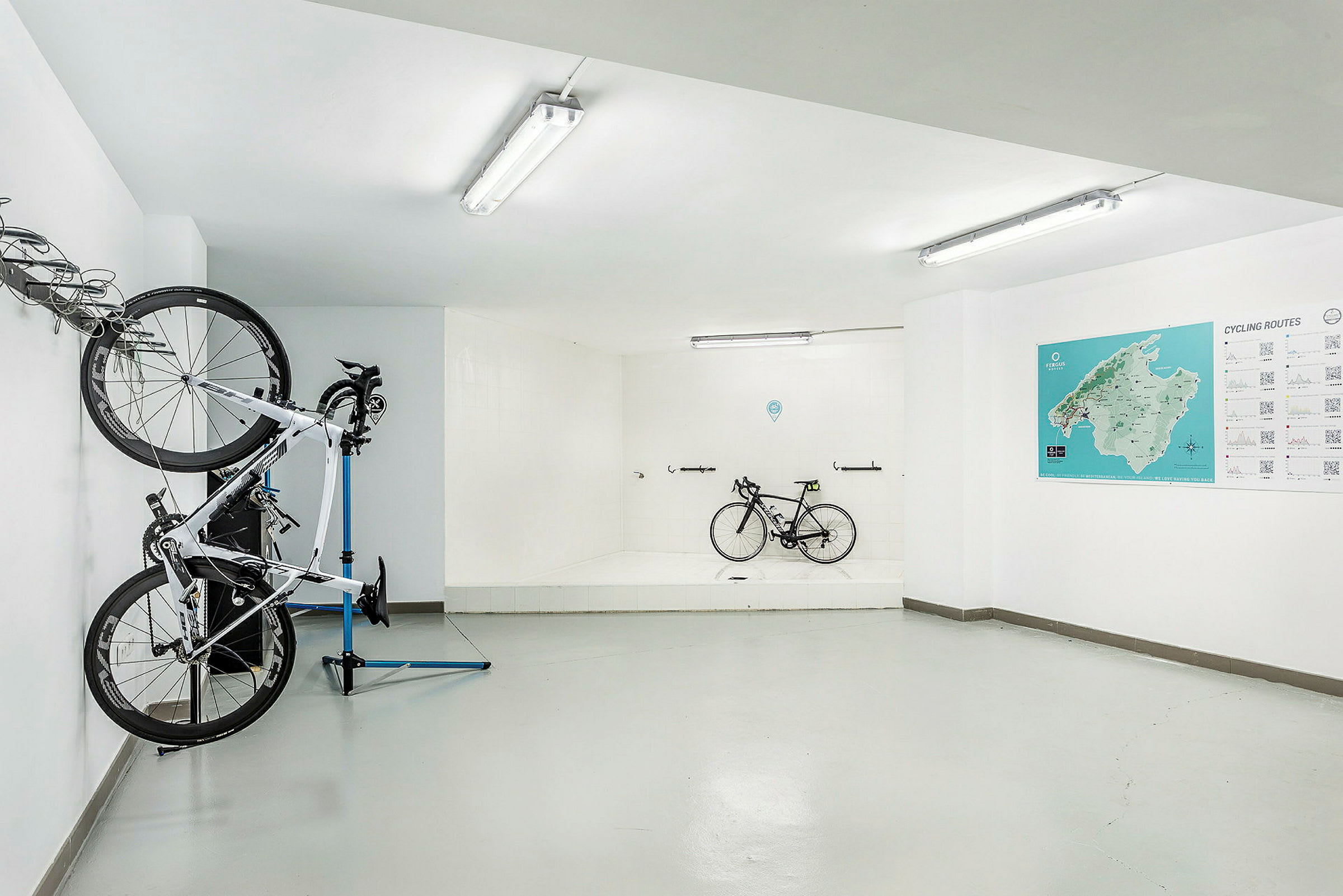 Cykelrum med hængende og stående cykler samt kort og information på væggen. (AI-genereret tekst)