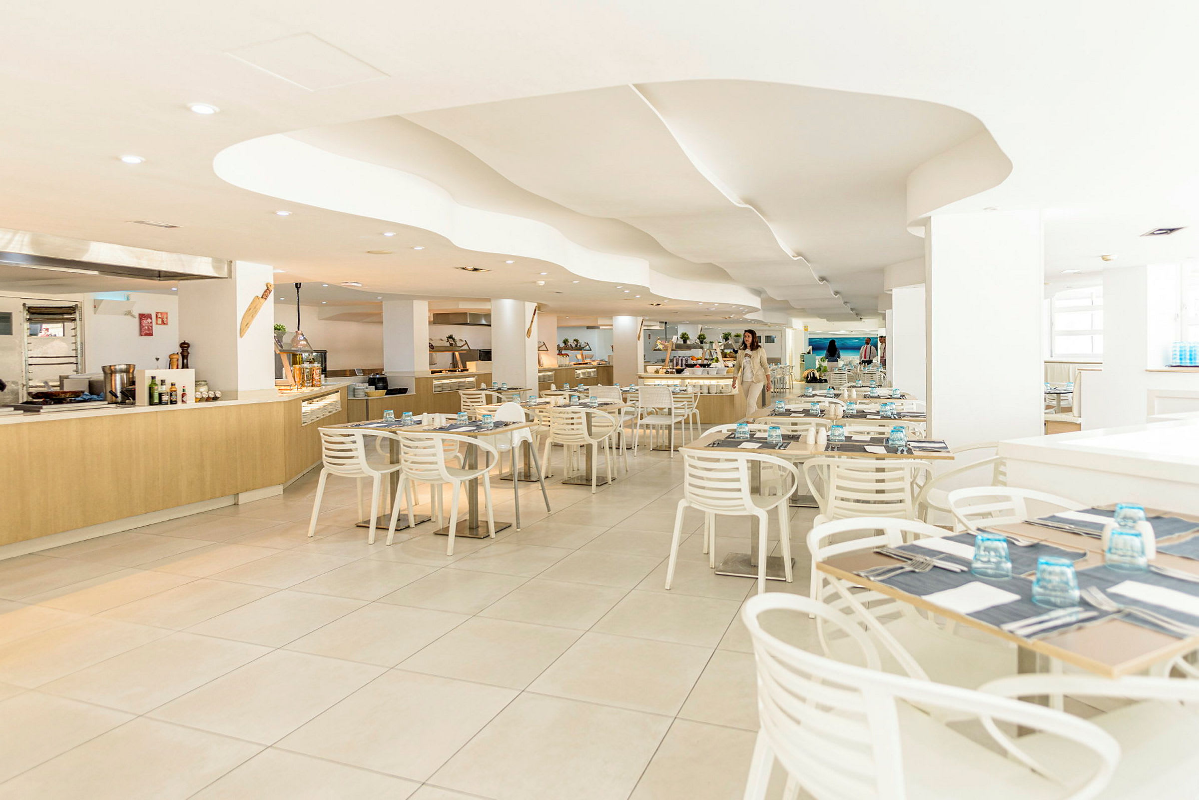 Interiør af en moderne restaurant med lyse møbler og dækkede borde. (AI-genereret tekst)