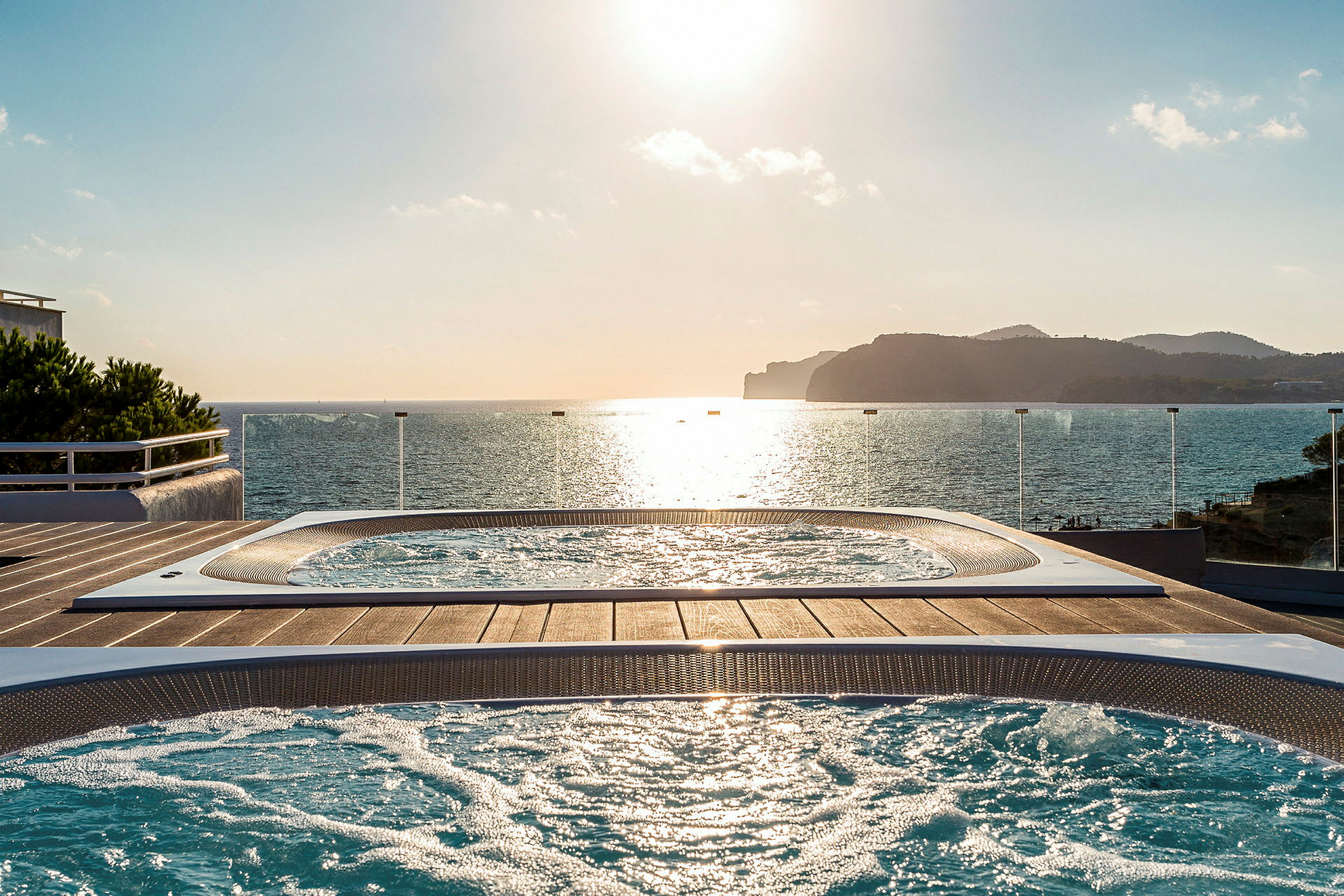 To jacuzzi-bassiner på en terrasse med udsigt over havet ved solnedgang. (AI-genereret tekst)