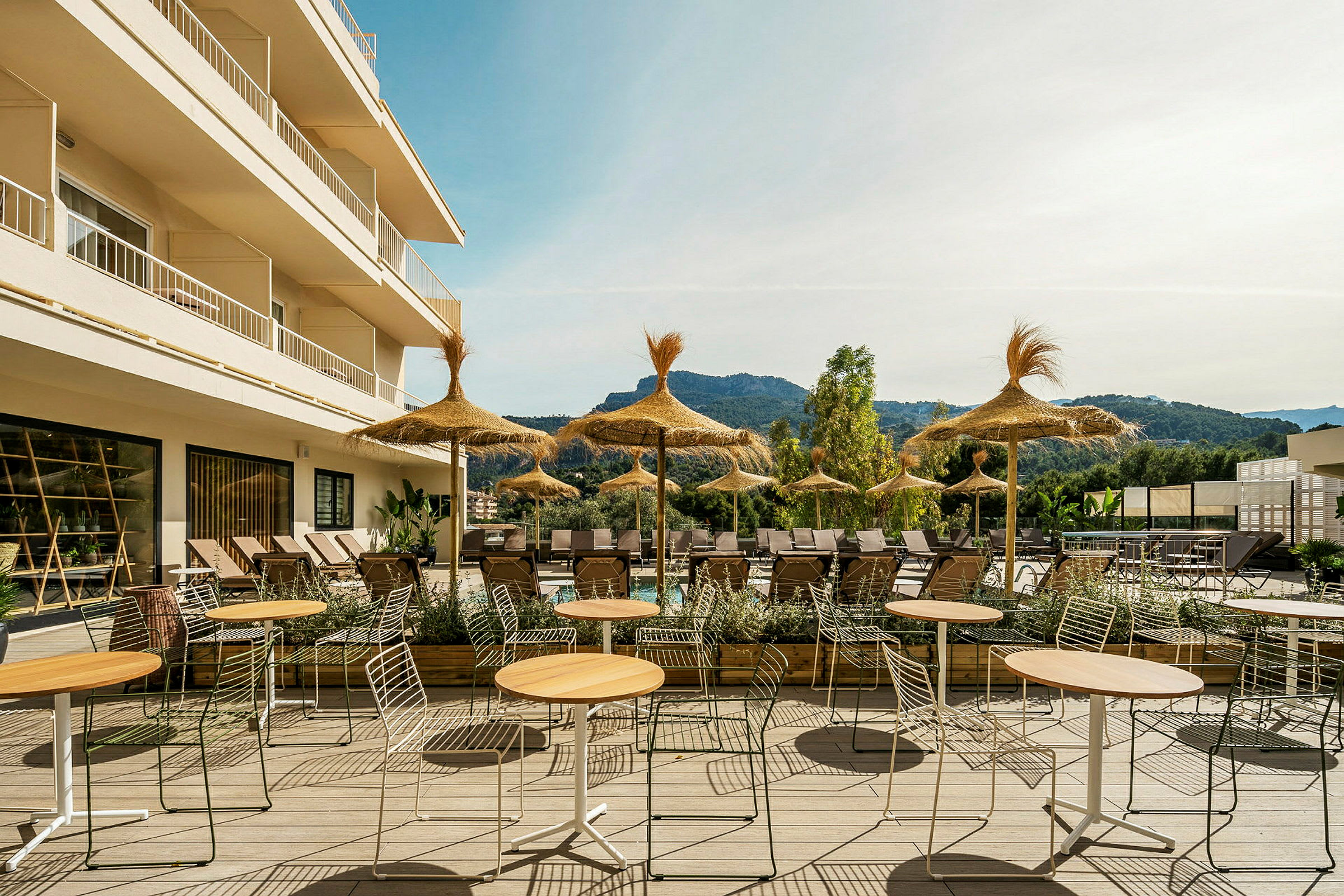 Udendørsområde med borde, stole og parasoller ved en solrig terrasse. (AI-genereret tekst)