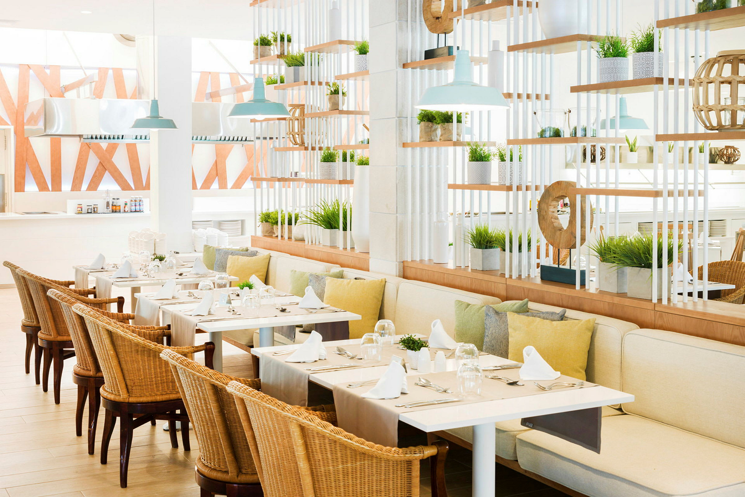 Billede af en lys og luftig restaurant med borde dækket med hvide servietter og omgivet af planter. (AI-genereret tekst)