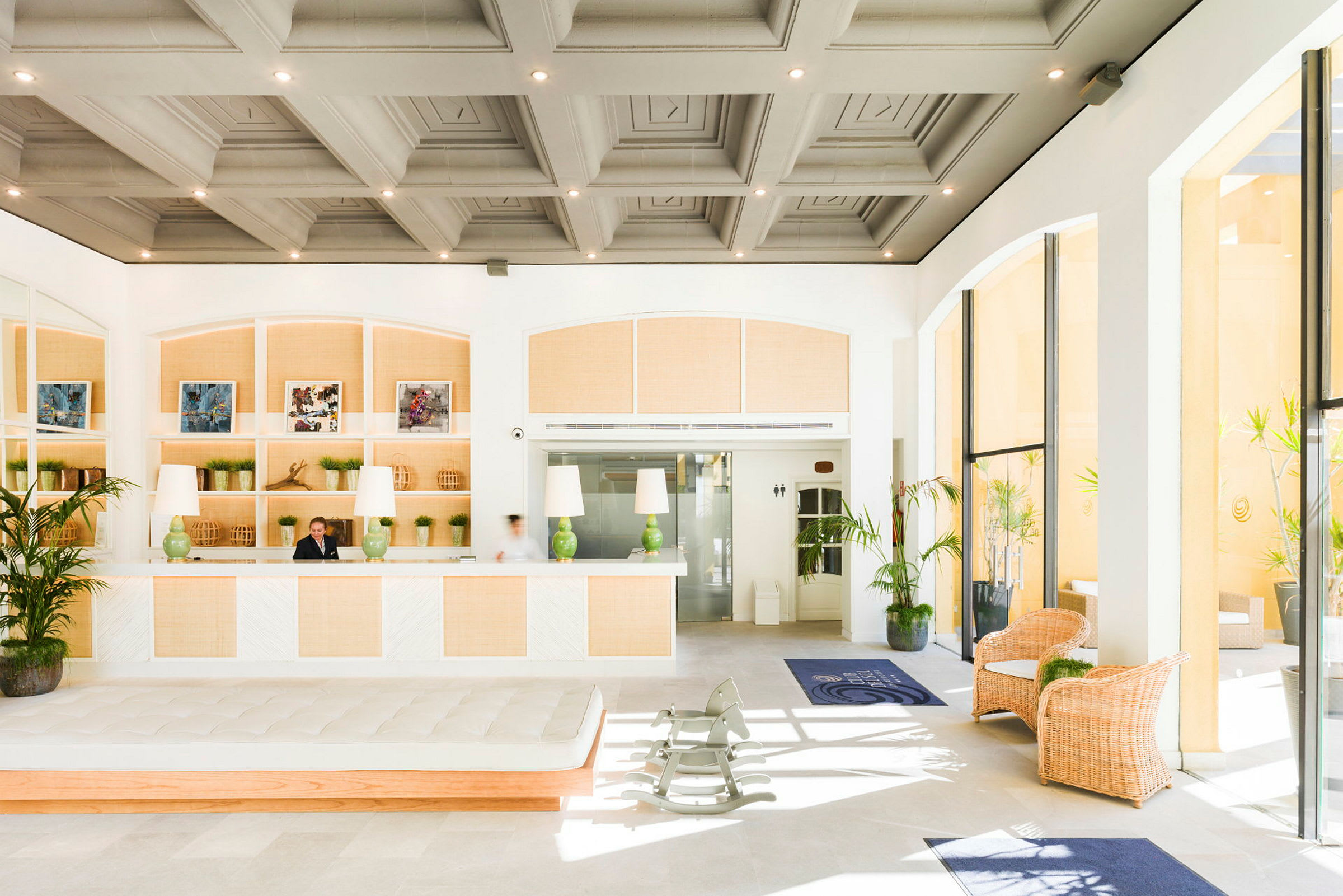 Lys og rummelig hotellobby med reception, planter og siddepladser. (AI-genereret tekst)