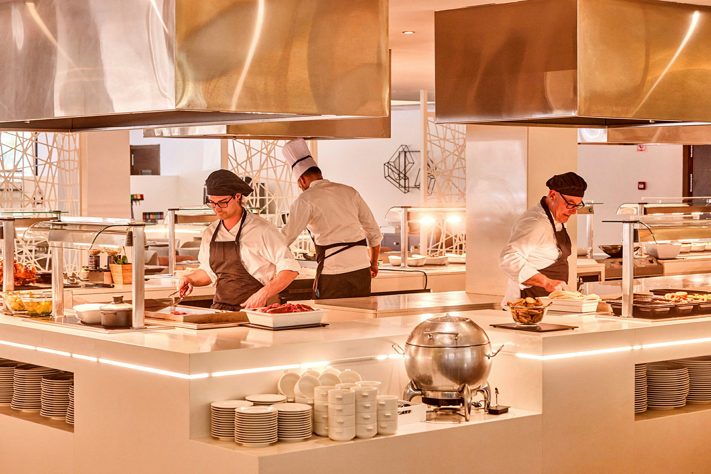 Kokke arbejder ved en moderne buffetstation i et oplyst køkkenområde. (AI-genereret tekst)