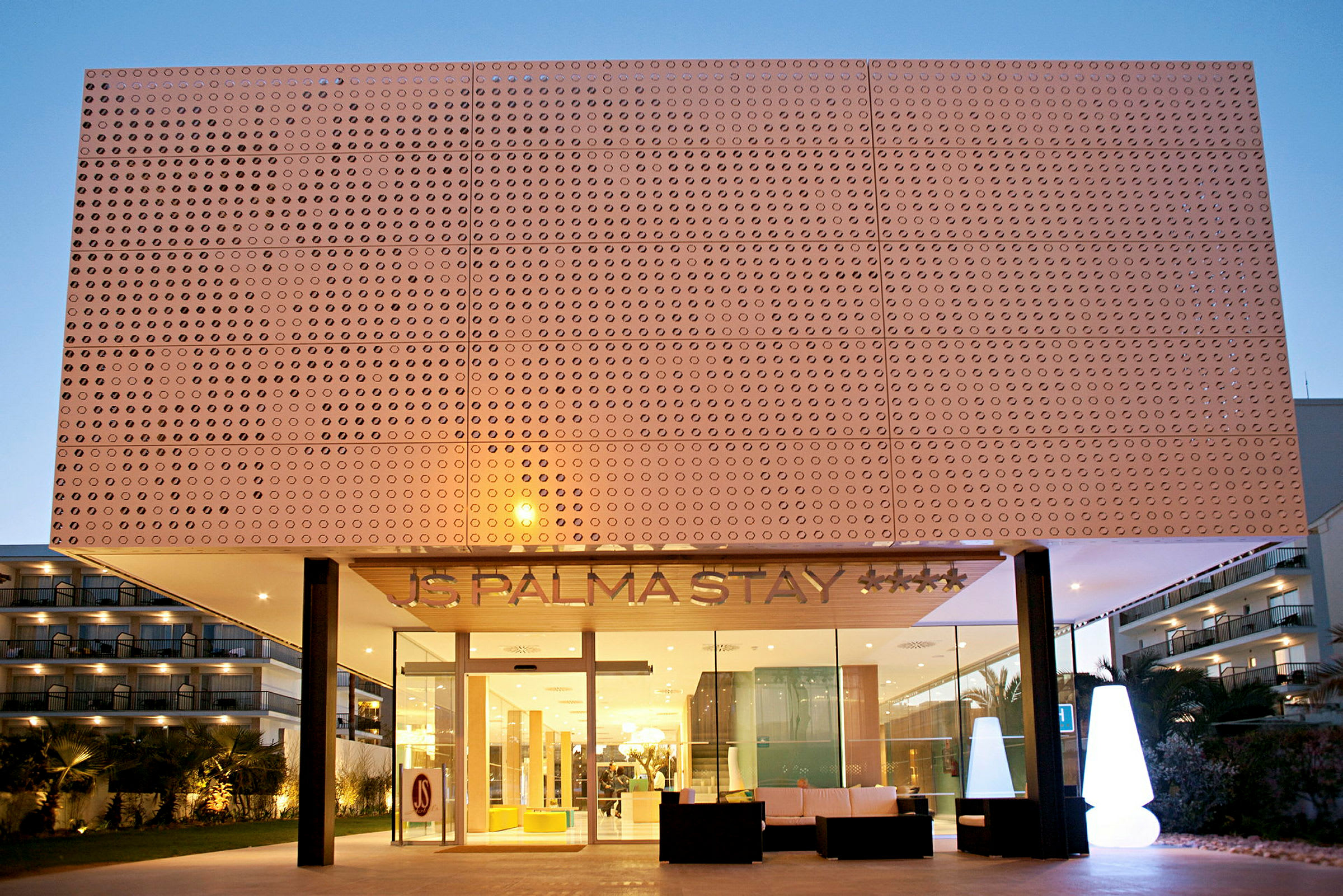 Hotelfacade med moderne design, synlige vinduer og indgangsområde med belysning. (AI-genereret tekst)