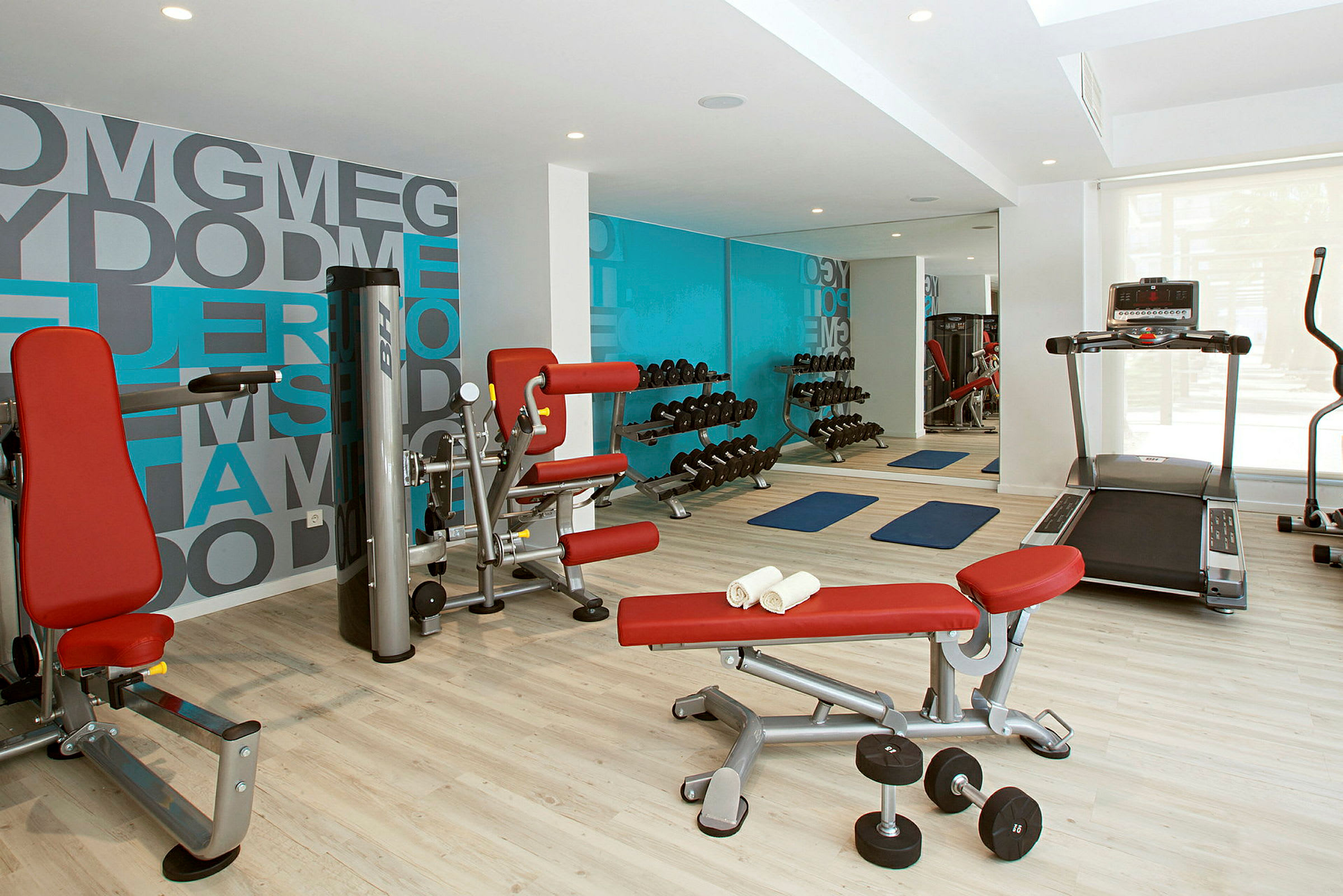 Et fitnesscenter med træningsmaskiner, håndvægte og yogamåtter. (AI-genereret tekst)
